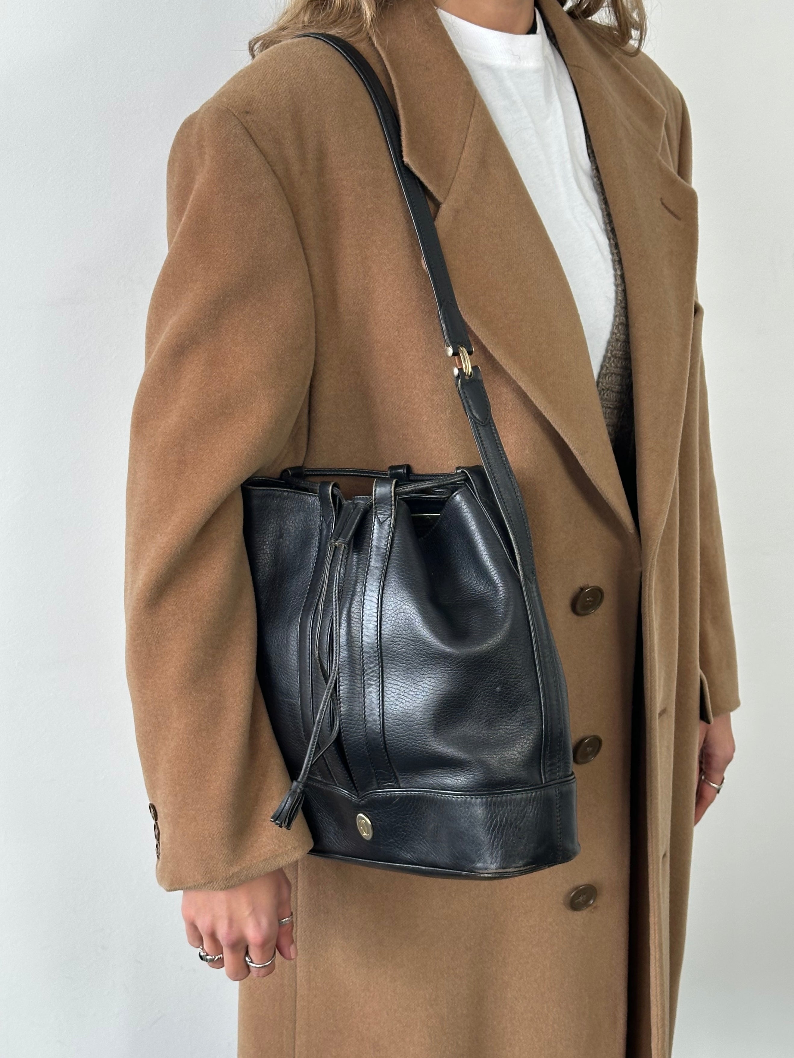 Cartier 1980s leather bucket bag with rounded design, drawstring closure, and shoulder strap, vintage luxury handbag.