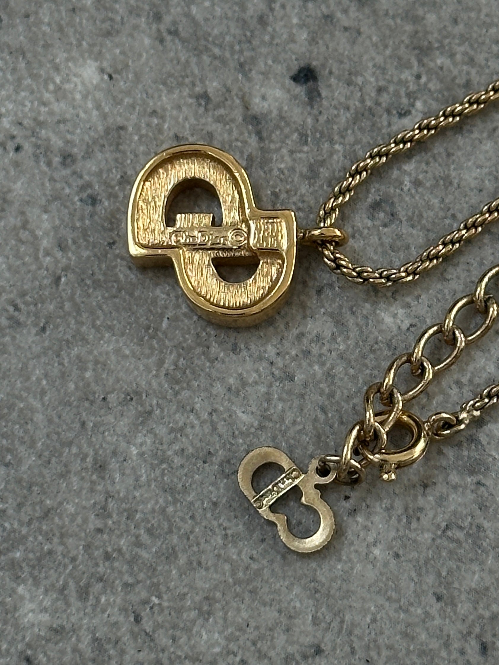 Christian Dior 16-inch gold plated rhinestone logo pendant necklace displayed with intricate details and sparkling rhinestones.