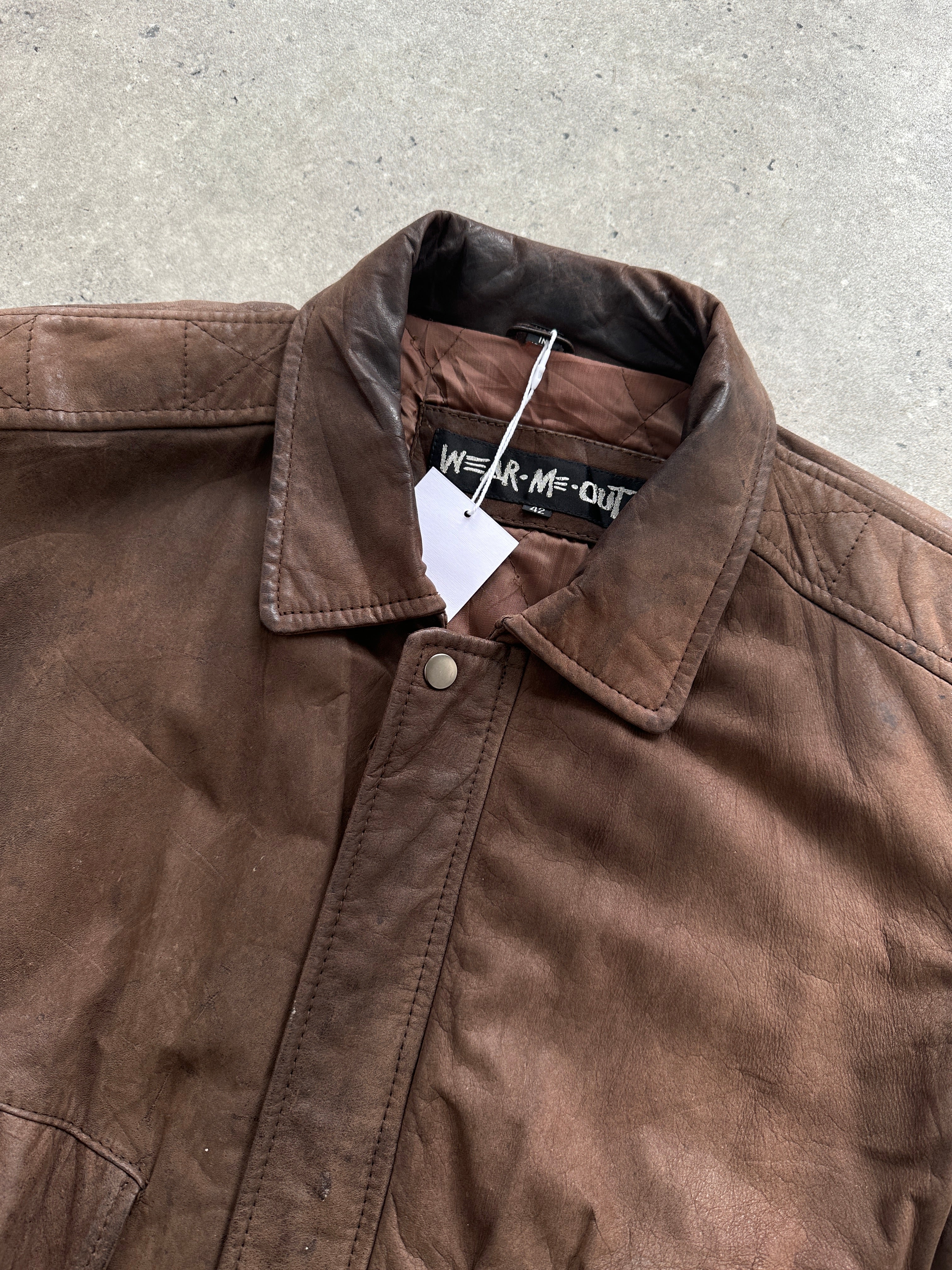 Vintage distressed leather bomber jacket, size large, showing rugged texture and classic style in natural lighting.