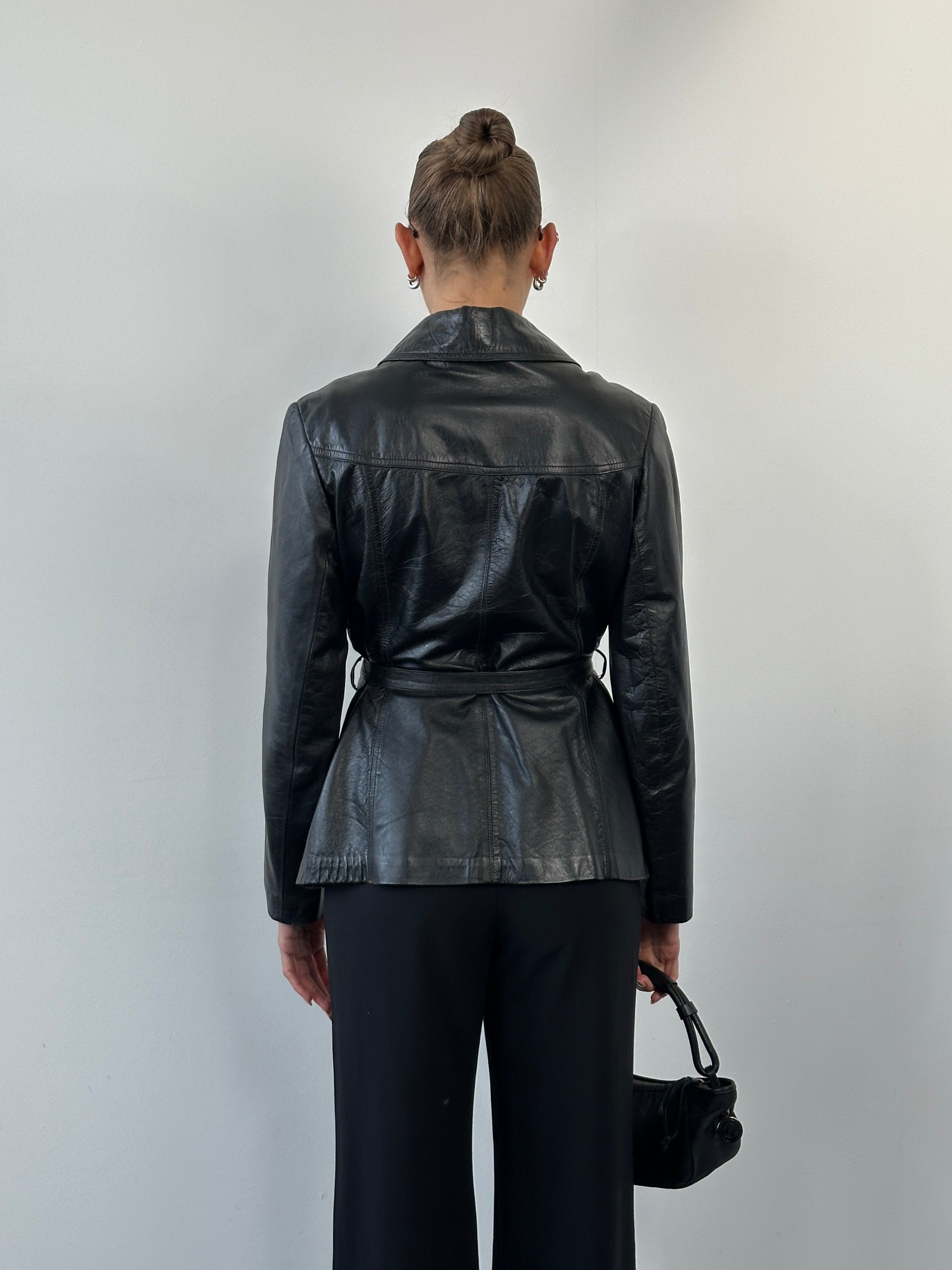 Vintage 1990s dagger collar leather jacket with belted waist, displayed on a hanger, in size M. Classic vintage leather style.