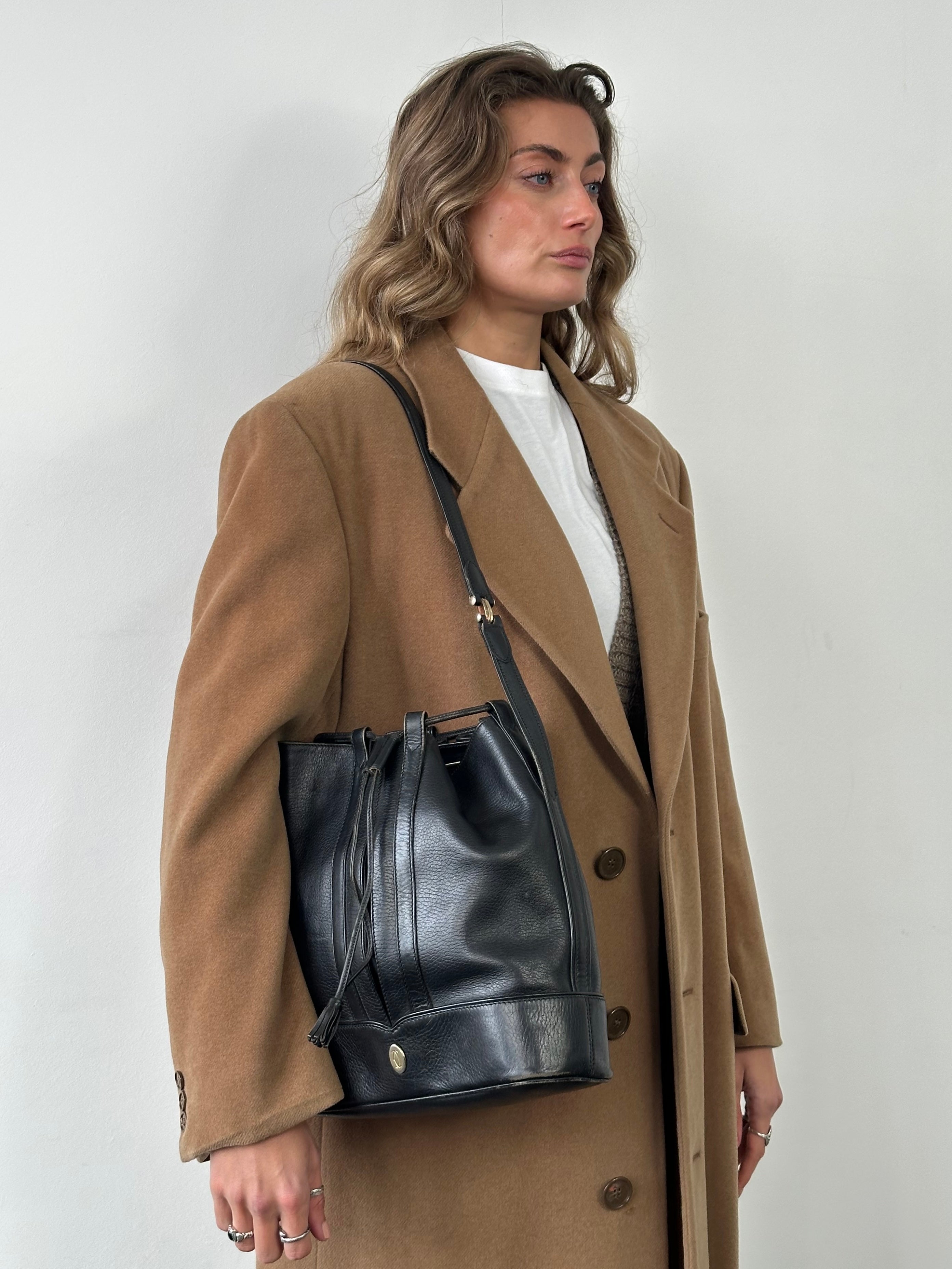 Cartier 1980s leather bucket bag with gold-tone hardware and top handle, showcasing vintage luxury style.