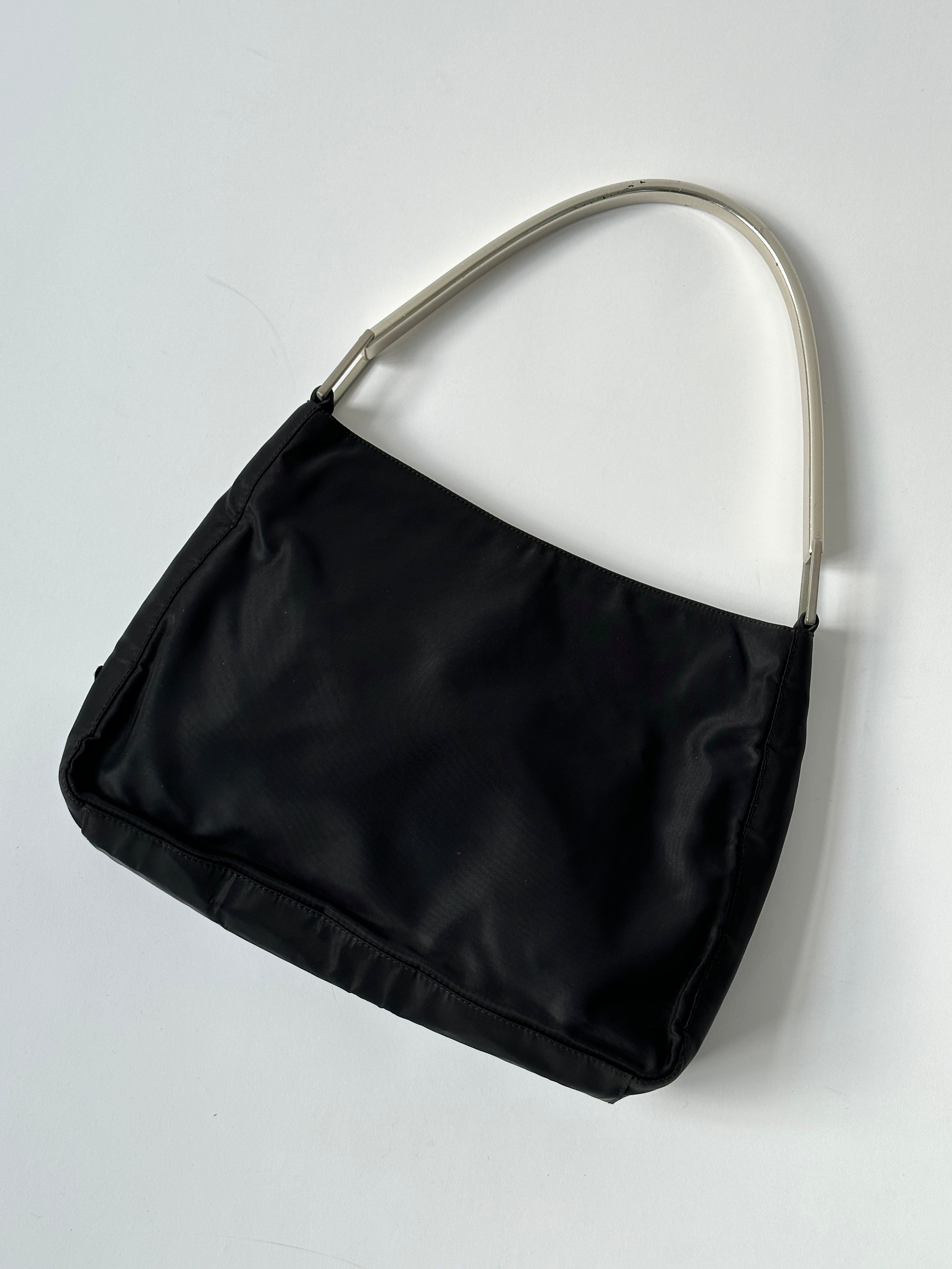 Prada nylon shoulder bag with metal handle, featuring a sleek design and durable material for stylish everyday use.