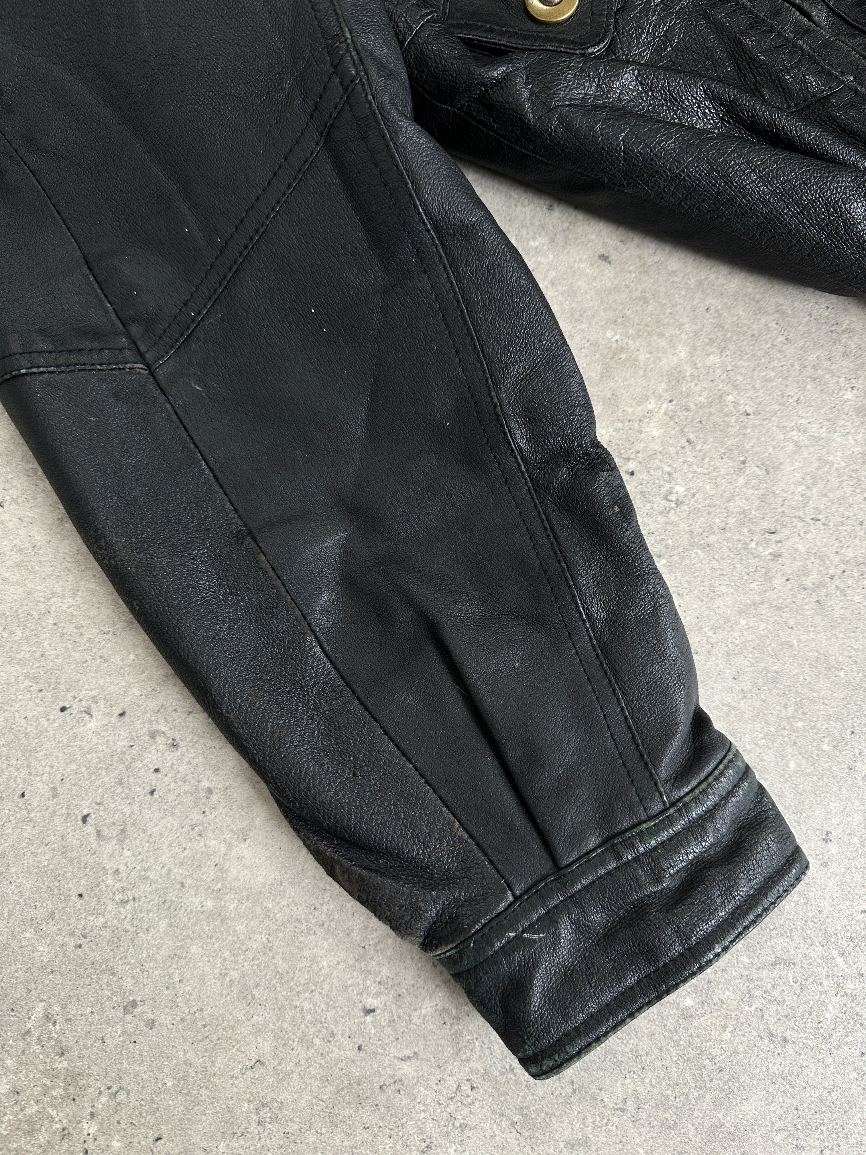 Vintage leather bomber jacket in size L/XL, featuring classic design and rugged texture, displayed on a hanger.