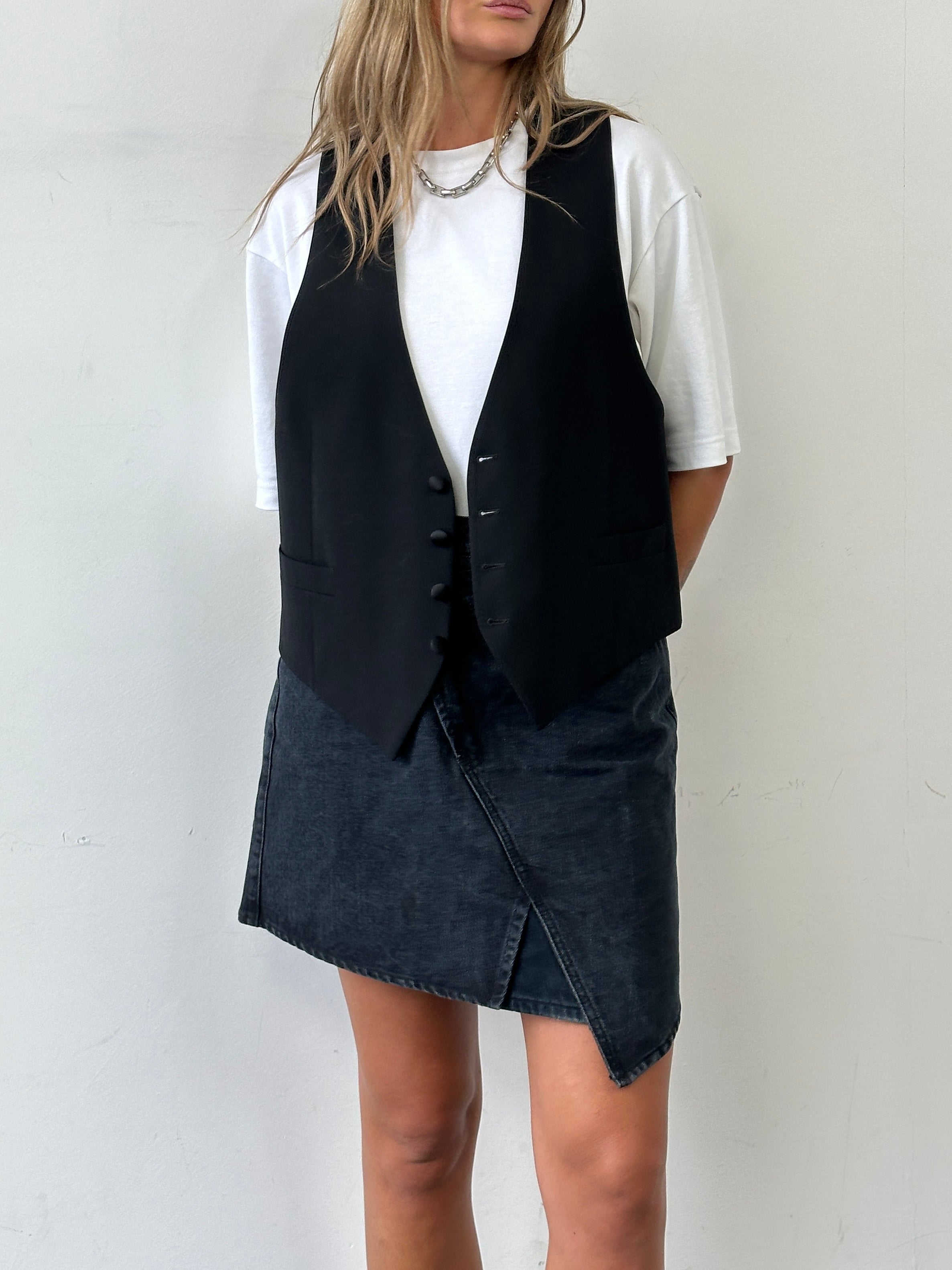 Vintage asymmetrical denim mini skirt with distressed details and a high waist, styled for a casual, vintage look.
