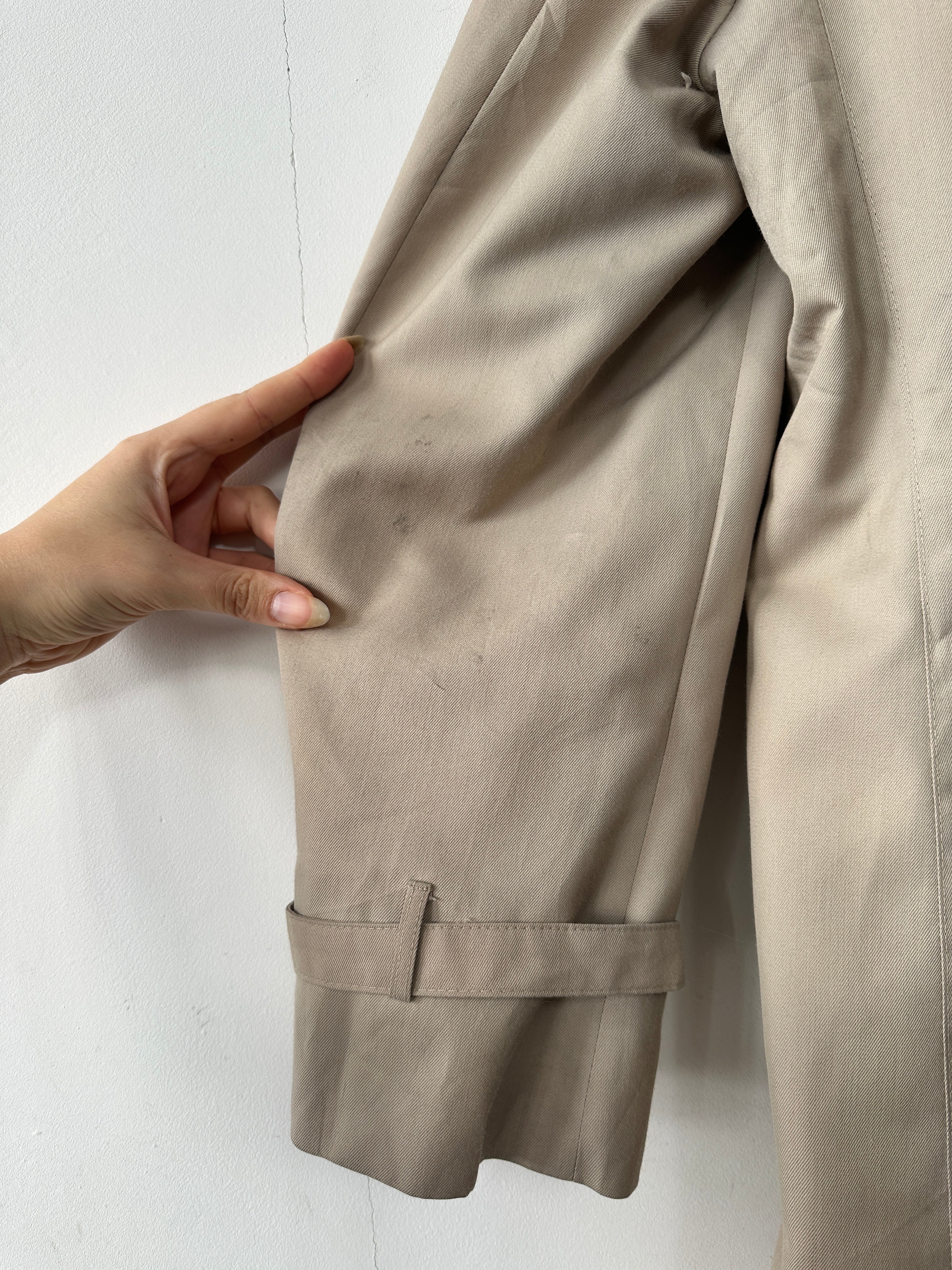 Christian Dior double-breasted trench coat in XL/XXL, shown hanging with classic beige fabric and stylish belt details.
