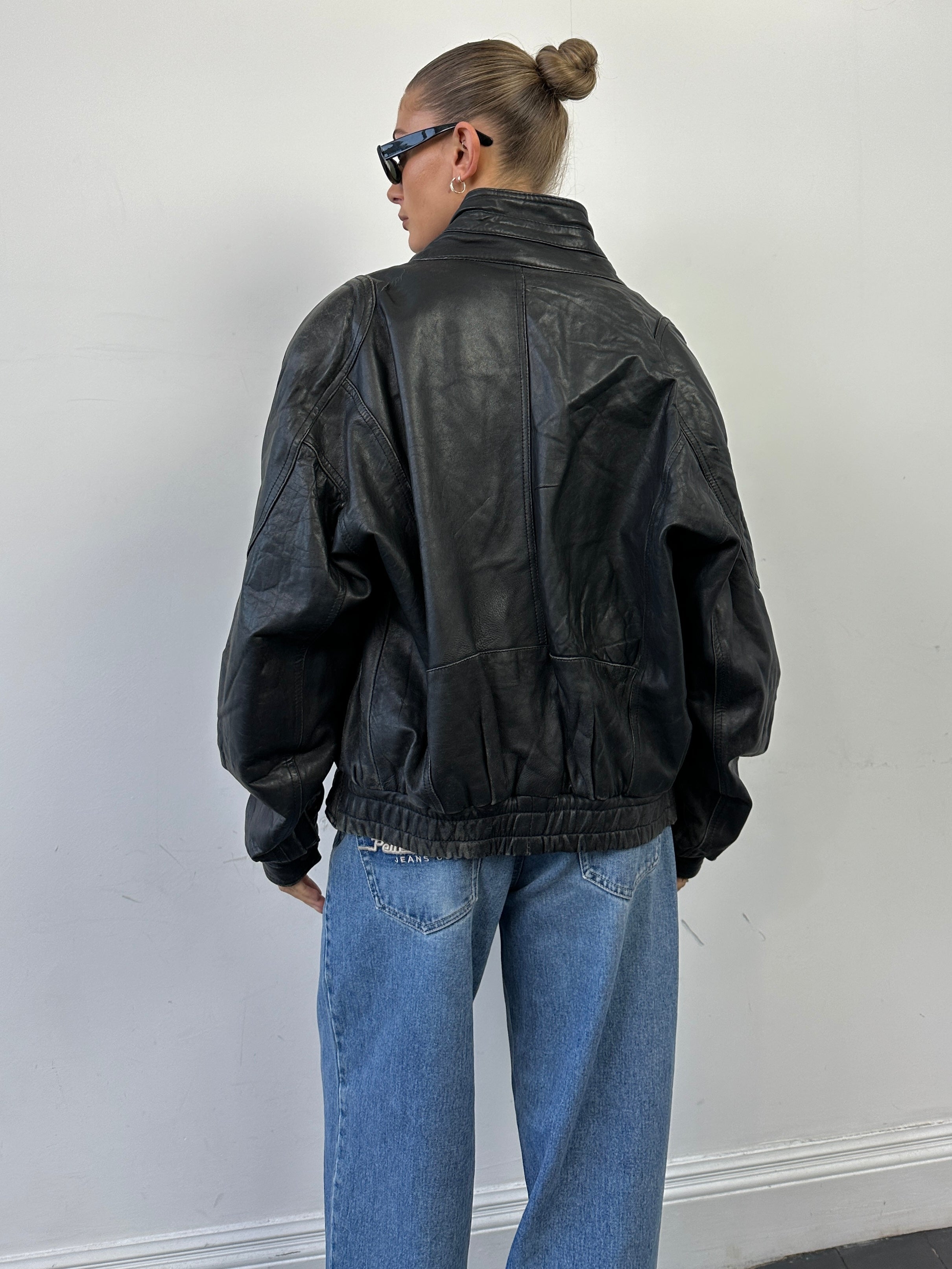 Vintage leather bomber jacket in size M, featuring classic design with detailed stitching and a rugged, timeless look.