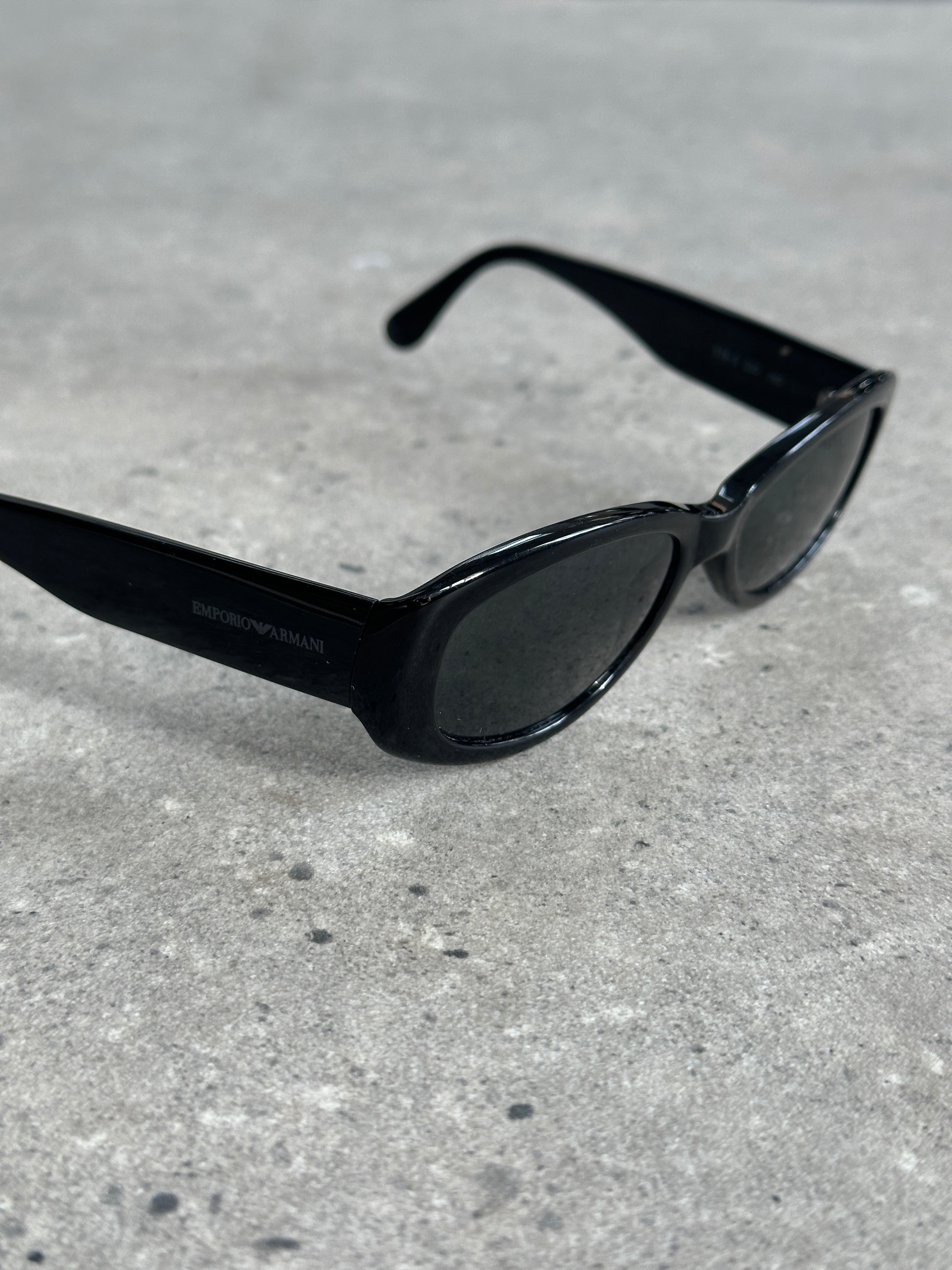 Emporio Armani oval sunglasses with dark tinted lenses and sleek black frames, stylish accessory for sun protection.