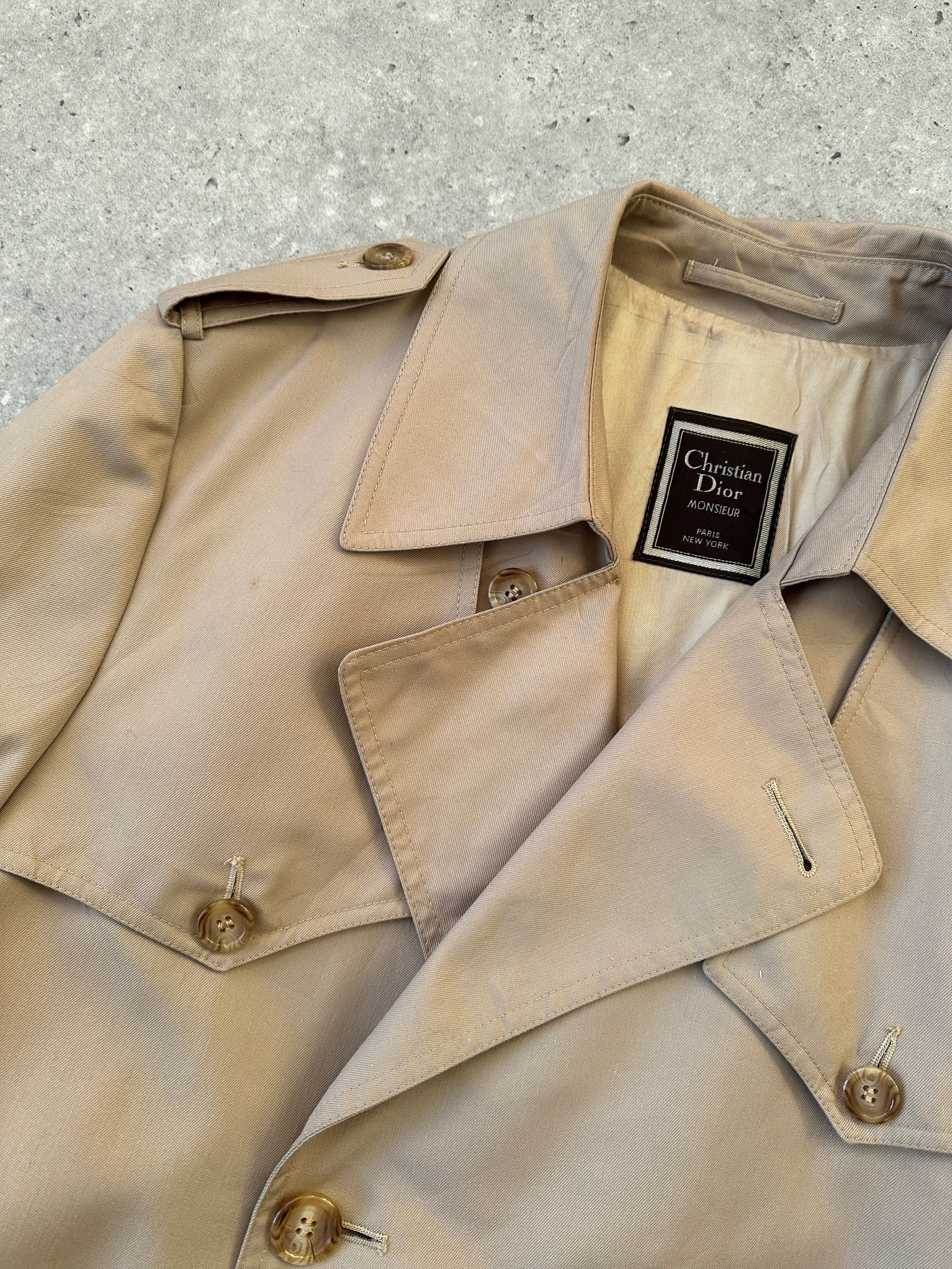 Christian Dior double-breasted cotton trench coat with belt, tailored fit, beige color, displayed on a hanger.