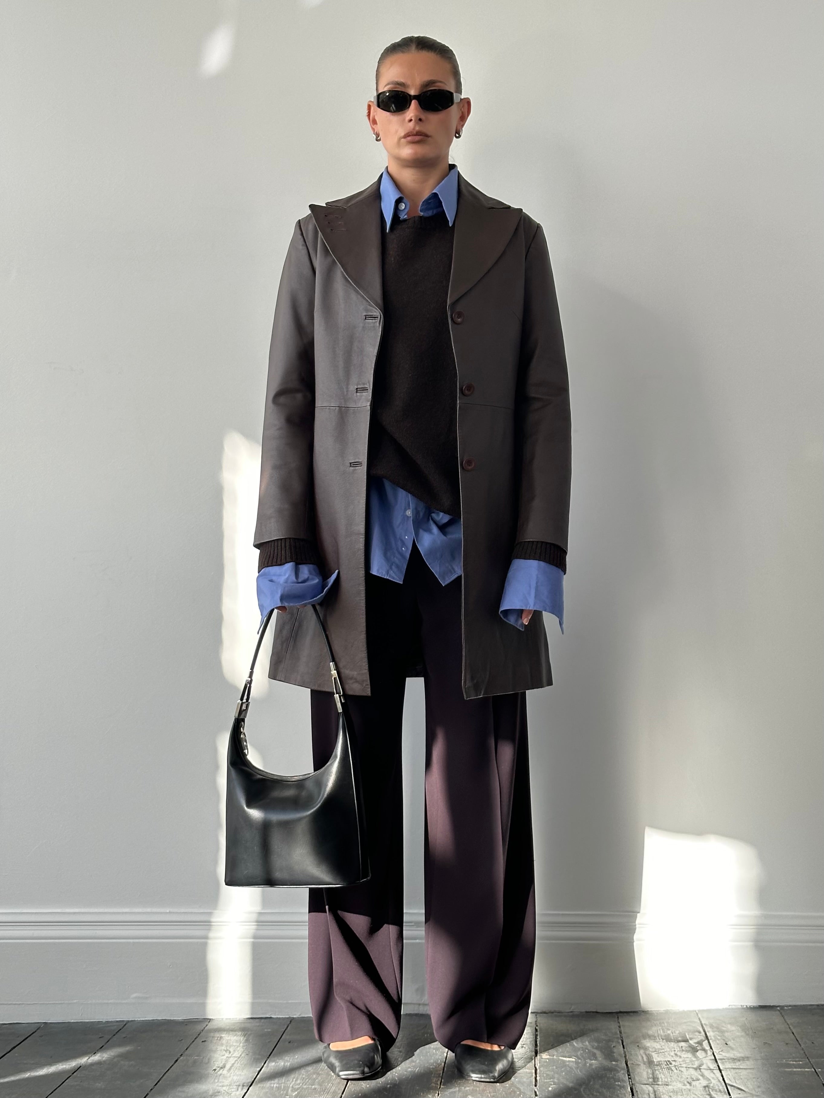 Vintage leather trench coat jacket in size M/L, featuring classic design and detailed stitching, displayed on a hanger.