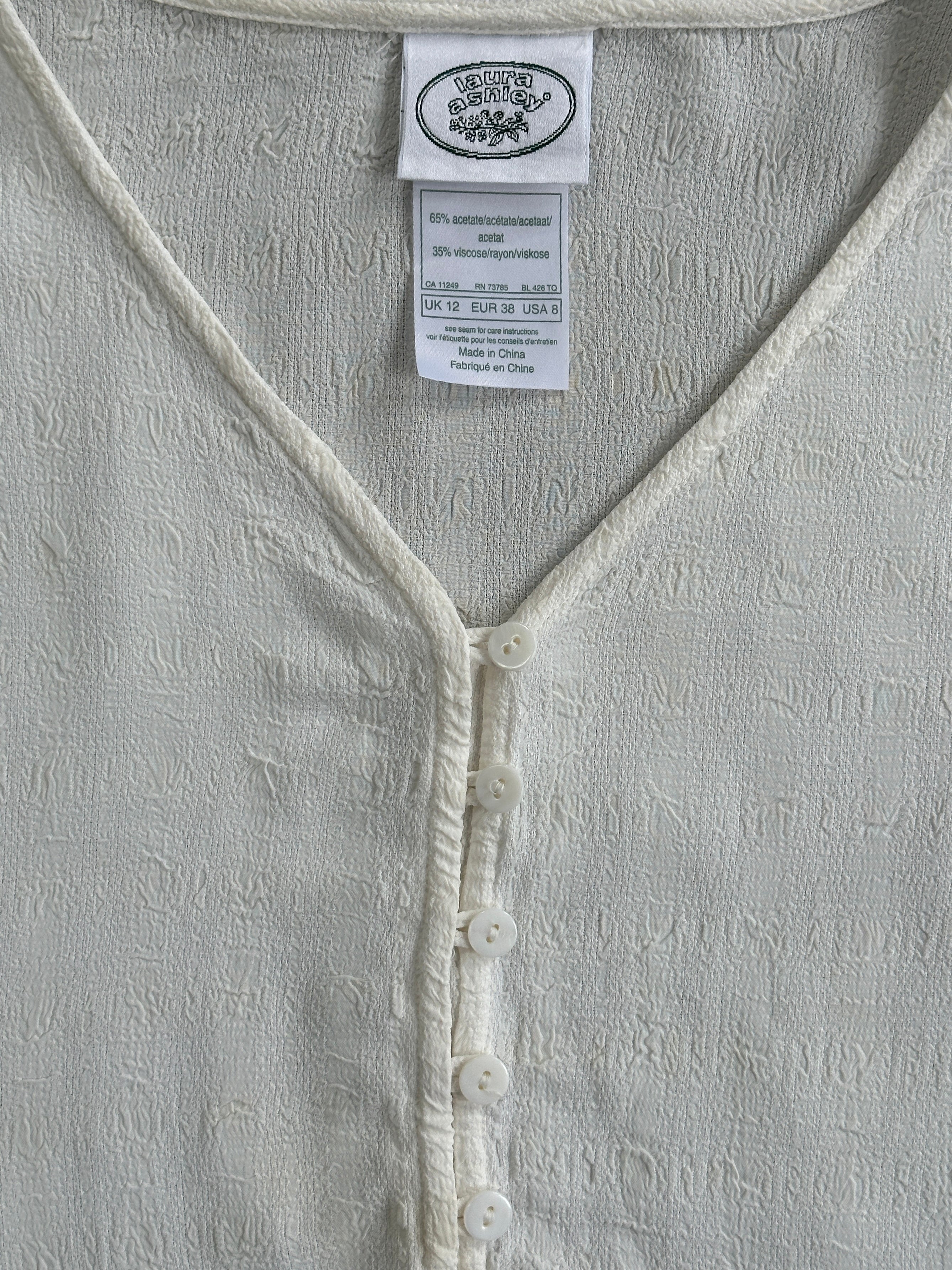 Laura Ashley textured collarless shirt in size M, featuring a stylish design and soft fabric, displayed on a hanger.