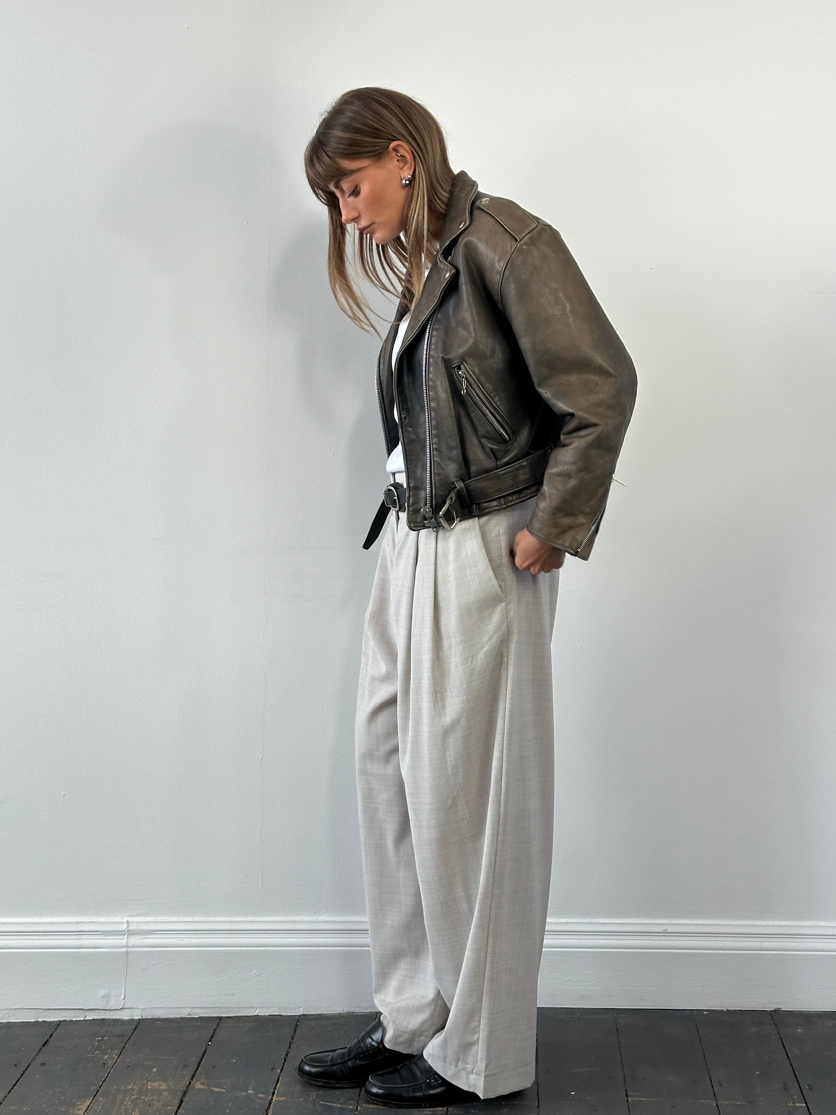 Vintage 1980s distressed leather biker jacket, small size, with rugged texture and classic motorcycle style.