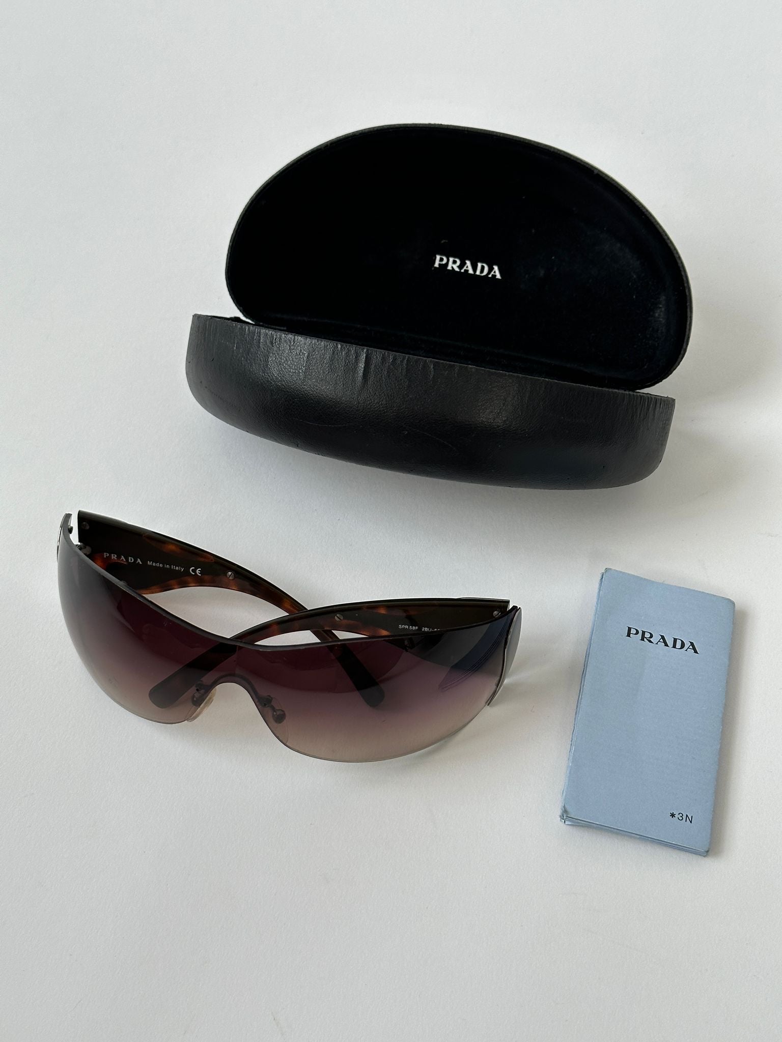 Prada Flame Rimless Wrap Sunglasses with sleek design, tinted lenses, and minimalist rimless frame for modern style and sun protection.