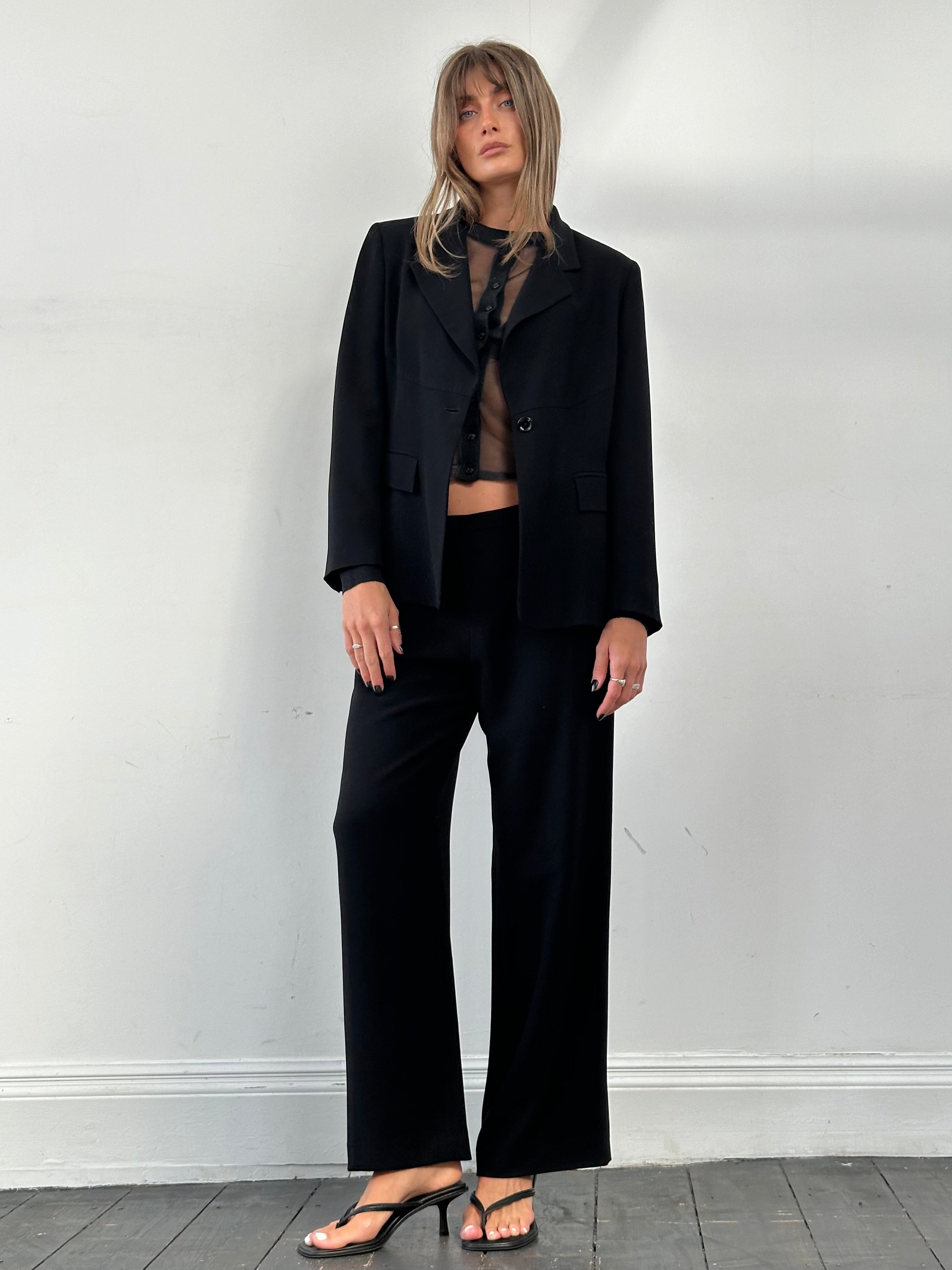 Max Mara minimal single-breasted jumpsuit in black, tailored fit with long sleeves and wide-leg design, front button closure.