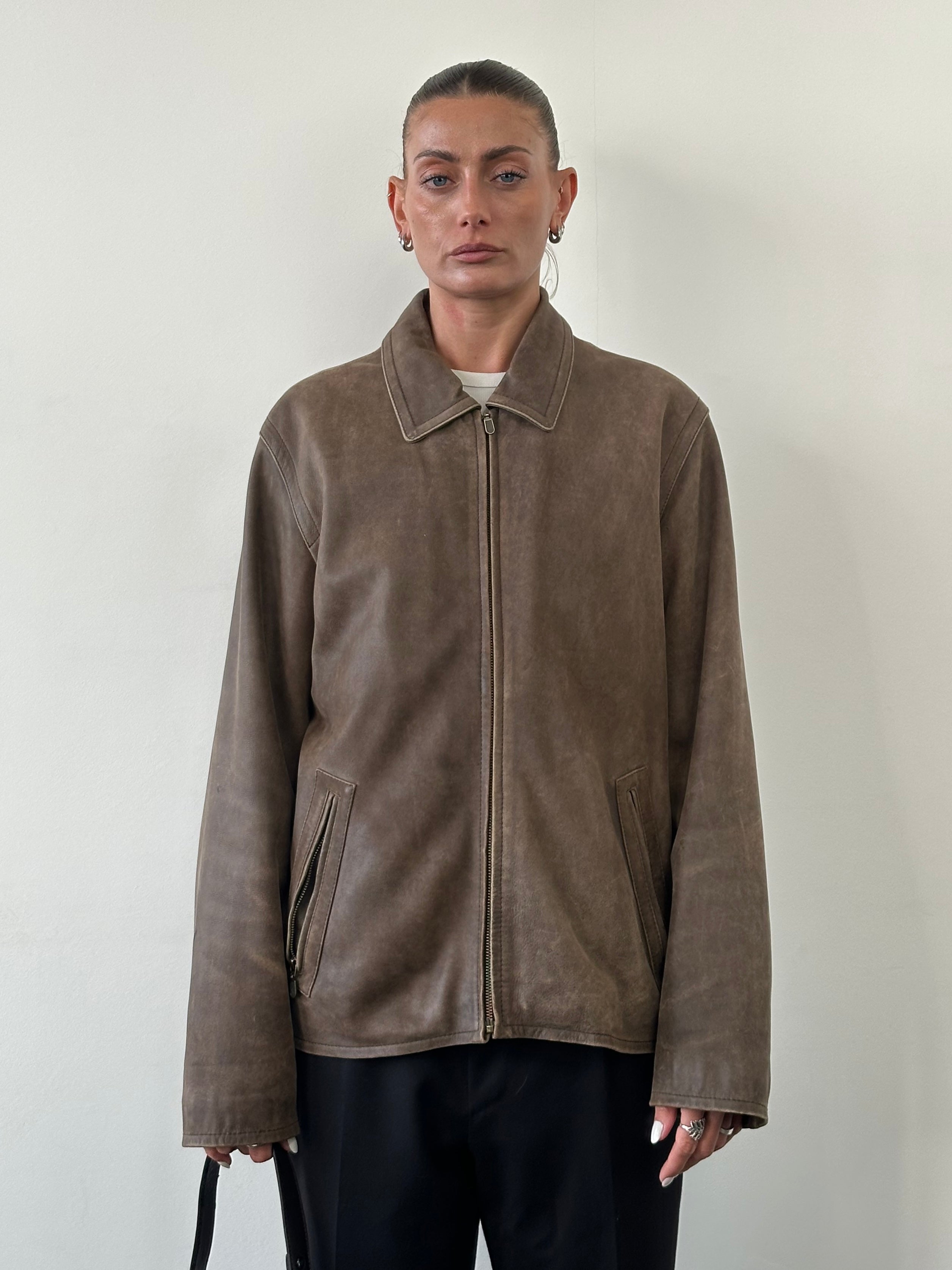 Vintage distressed leather jacket in size large, featuring rugged texture and classic style, displayed on a hanger.