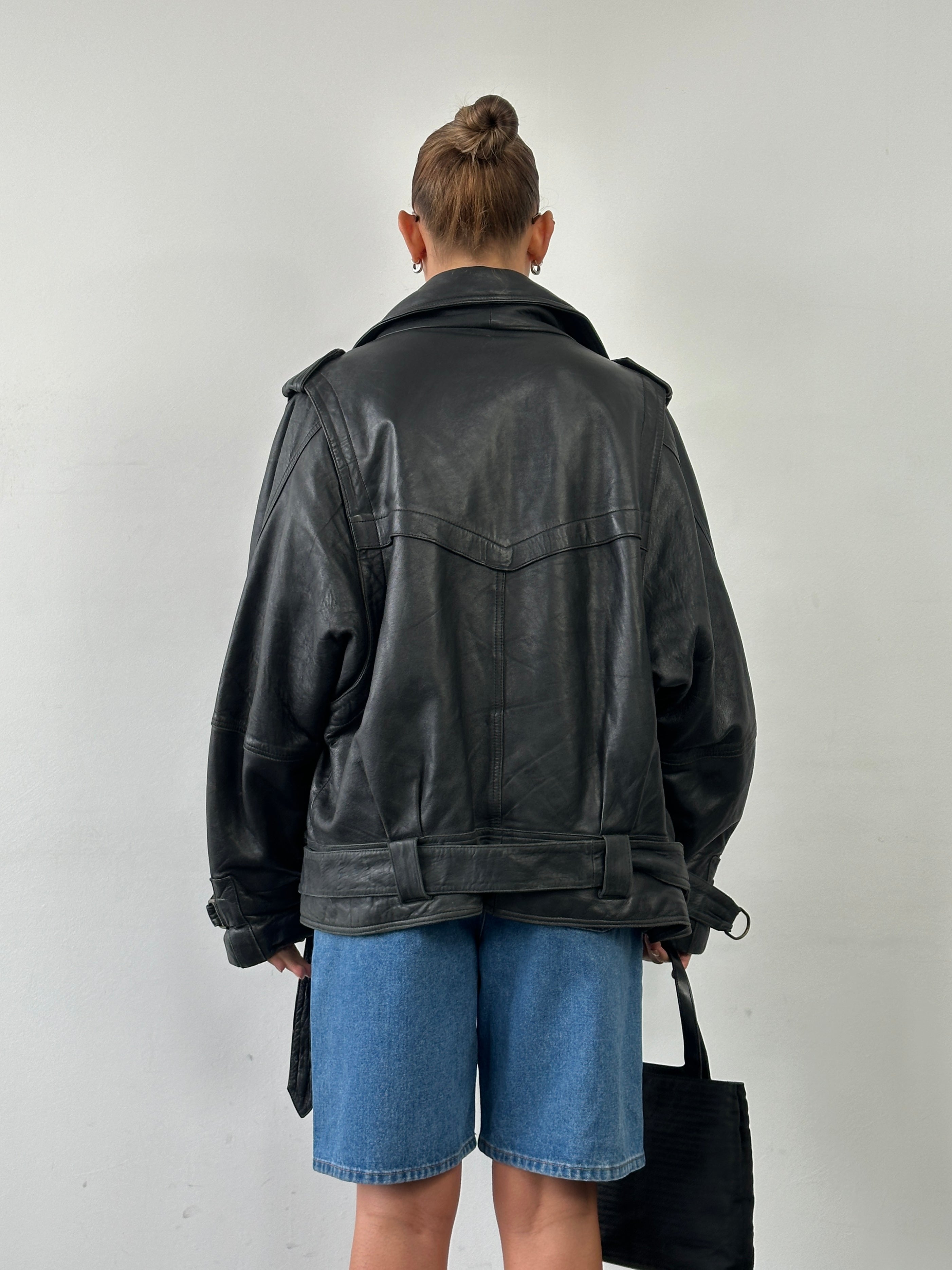 Vintage brand leather jacket with belted buckle in XL size, featuring classic design and visible leather texture.