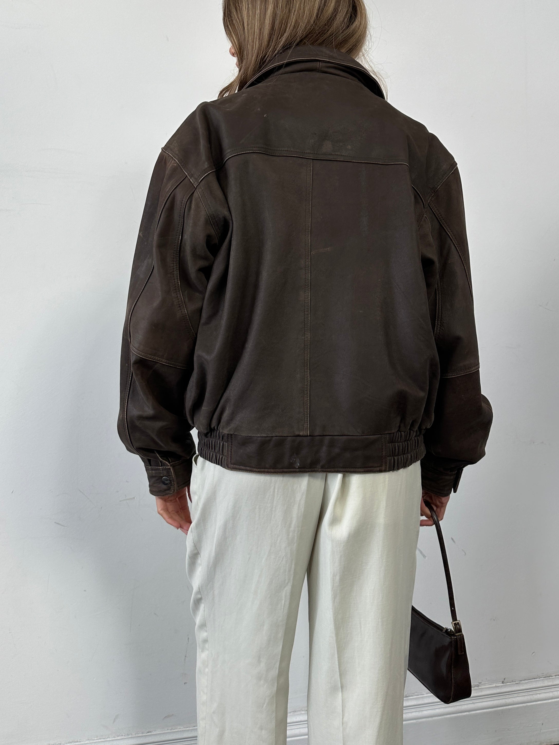 Vintage distressed leather bomber jacket for men, featuring a classic fit with rugged, worn-in detailing and a zip front.