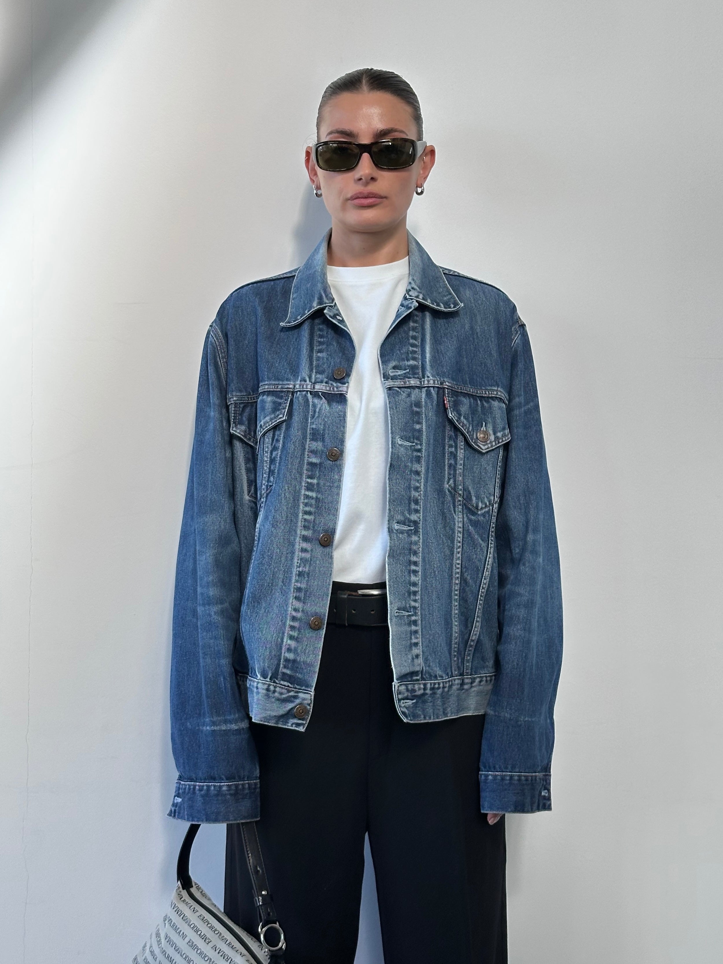 Levi’s faded denim jacket shown on a hanger, featuring classic blue denim with a slightly worn, vintage look.