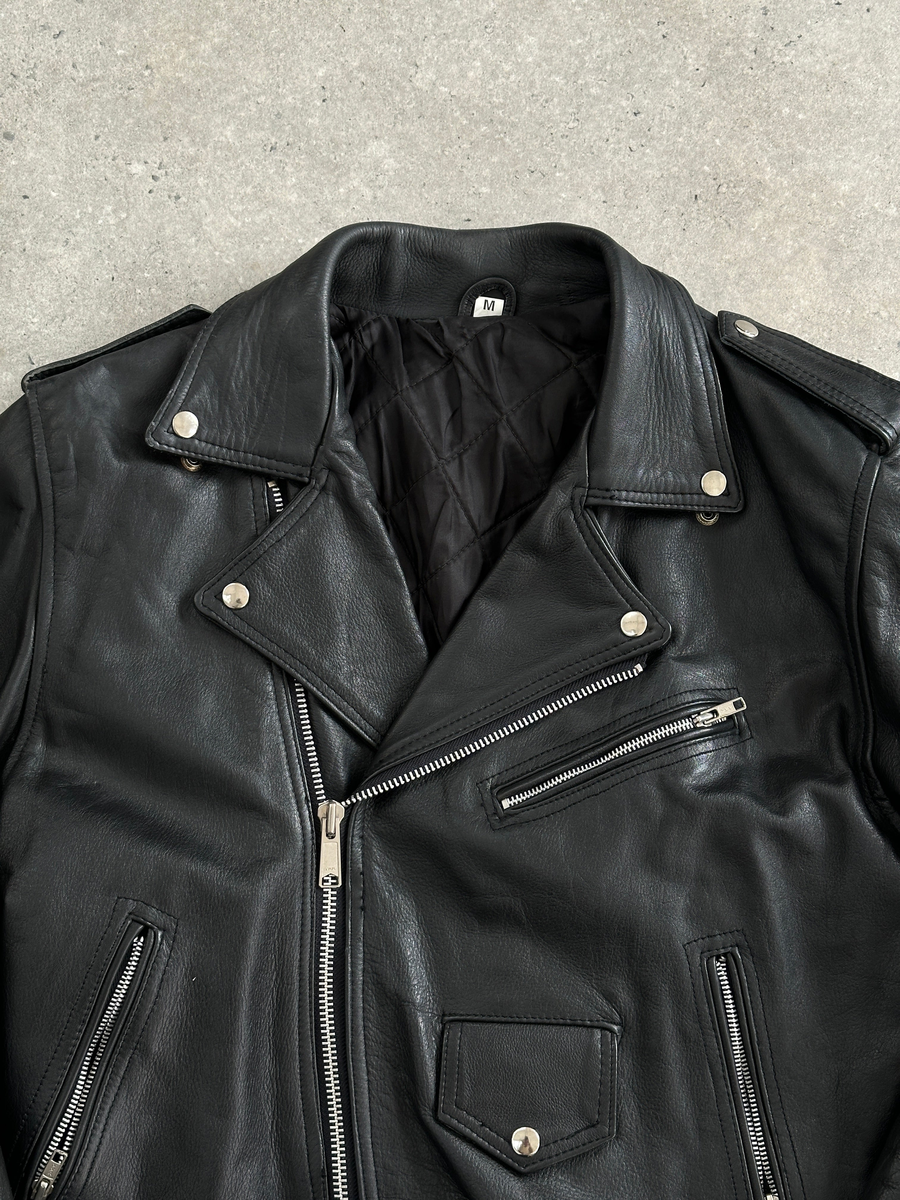 Vintage 1990s leather biker jacket in size M, featuring classic distressed leather and quilted detailing, vintage fashion style.