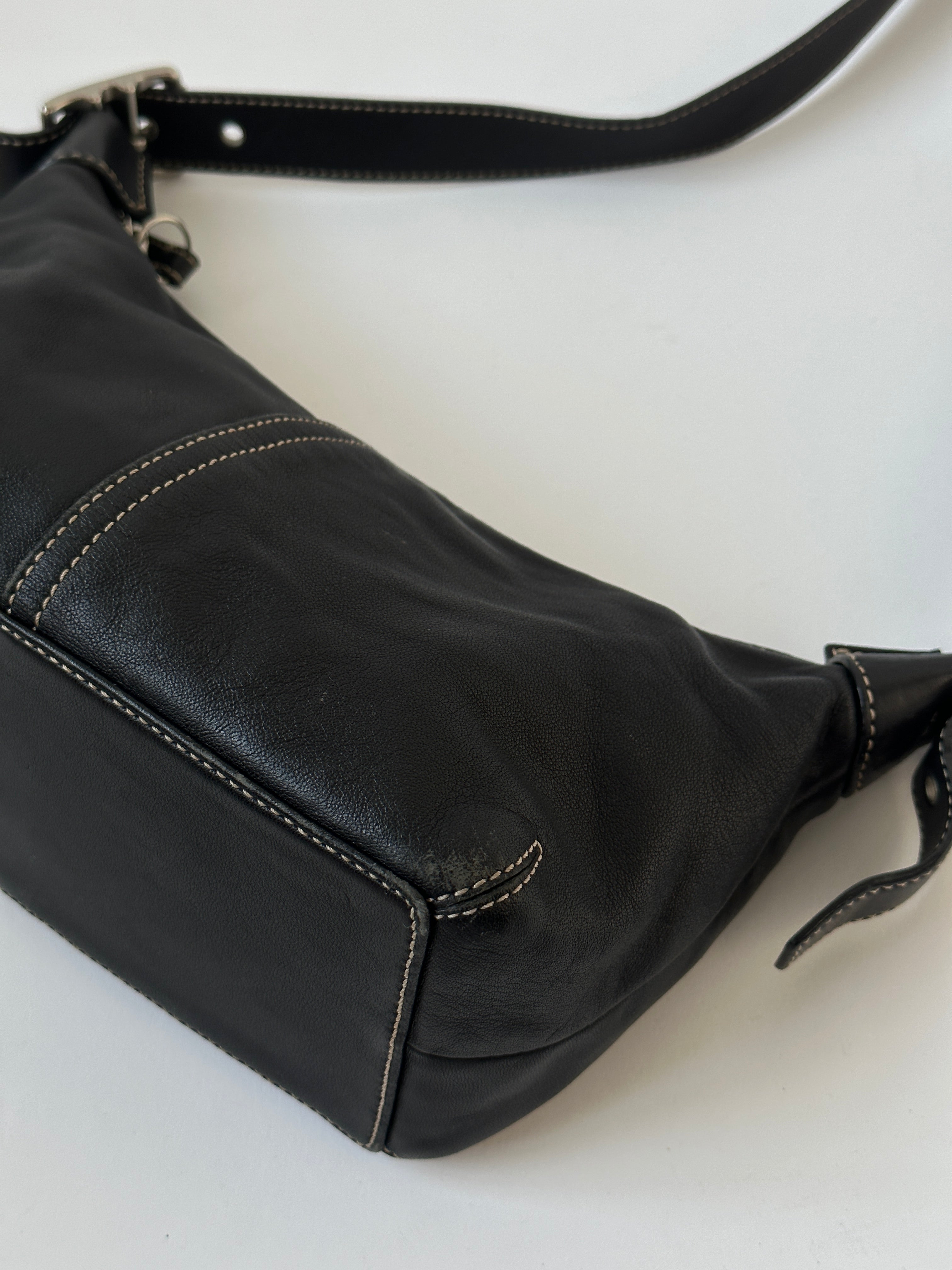Coach 2000s leather shoulder bag with contrast stitching, featuring a sleek design and adjustable strap, on a neutral background.