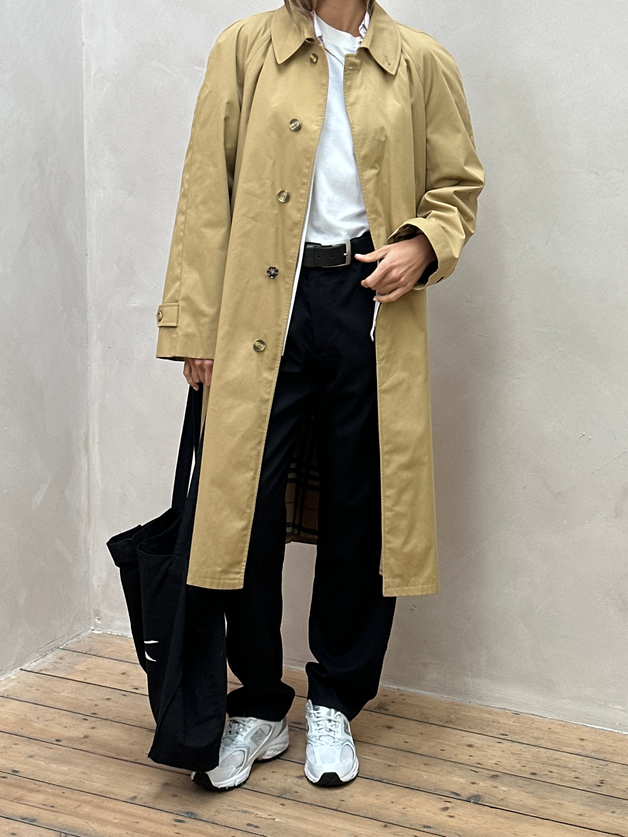 Vintage oversized trench coat with concealed placket and belt, featuring classic beige fabric and stylish collar detail.