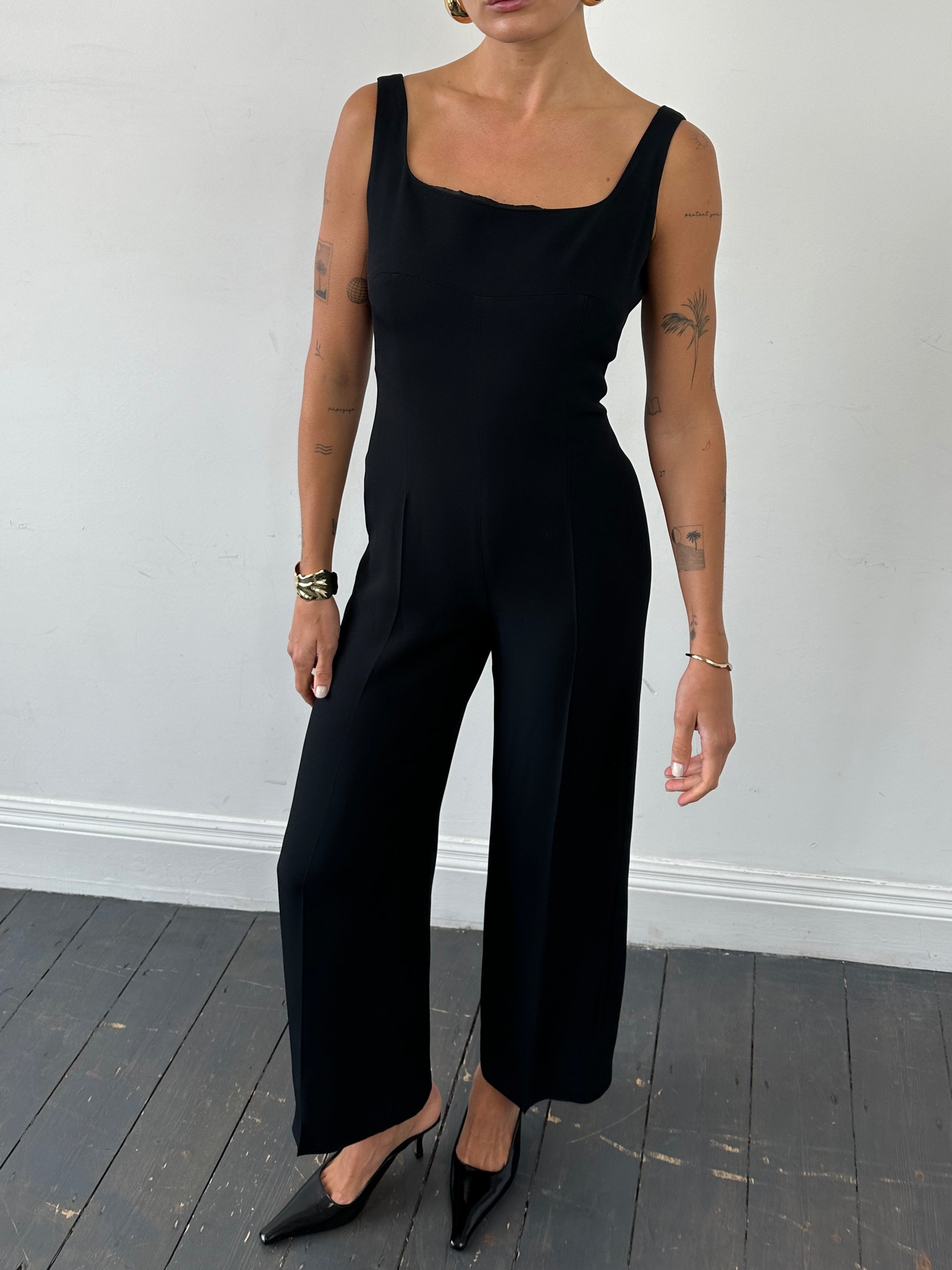 Max Mara square neck jumpsuit in black, featuring wide legs and sleeveless design, worn by a model in a studio setting.