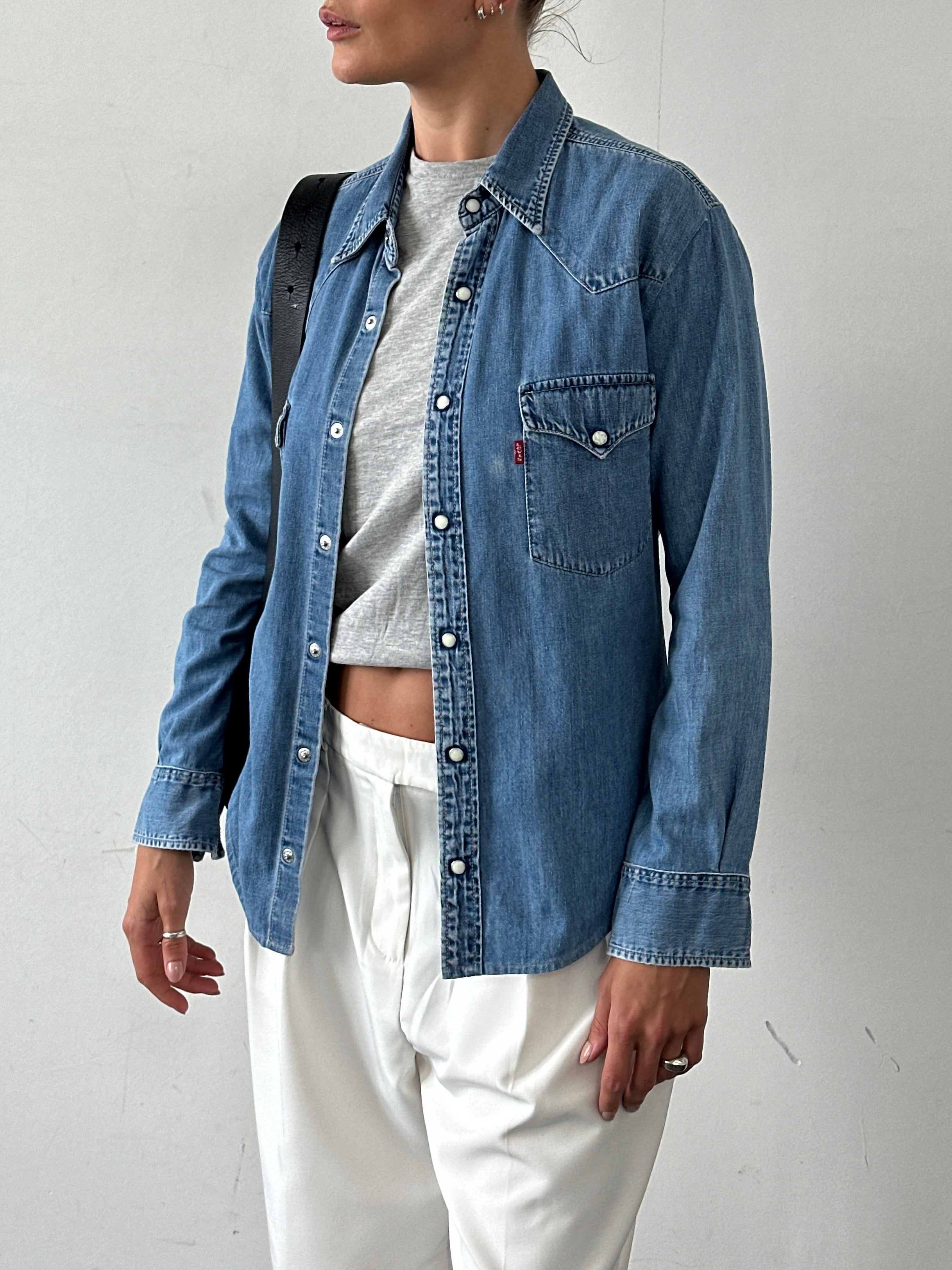 Levi’s cotton button-up denim shirt in size M, featuring classic blue denim fabric and front chest pockets.