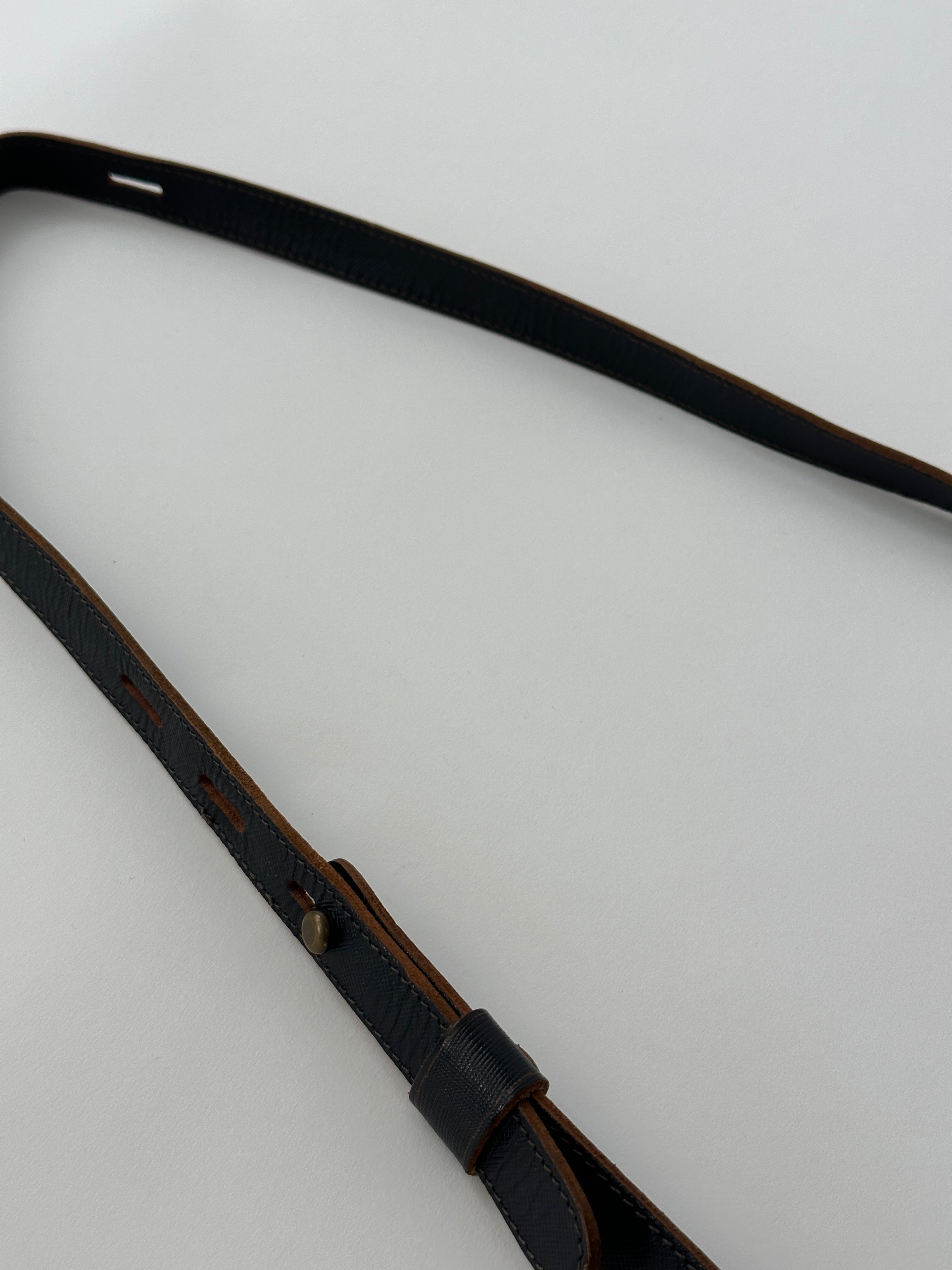 Vintage leather crossbody bag with adjustable strap and classic design, featuring visible stitching and a flap closure.