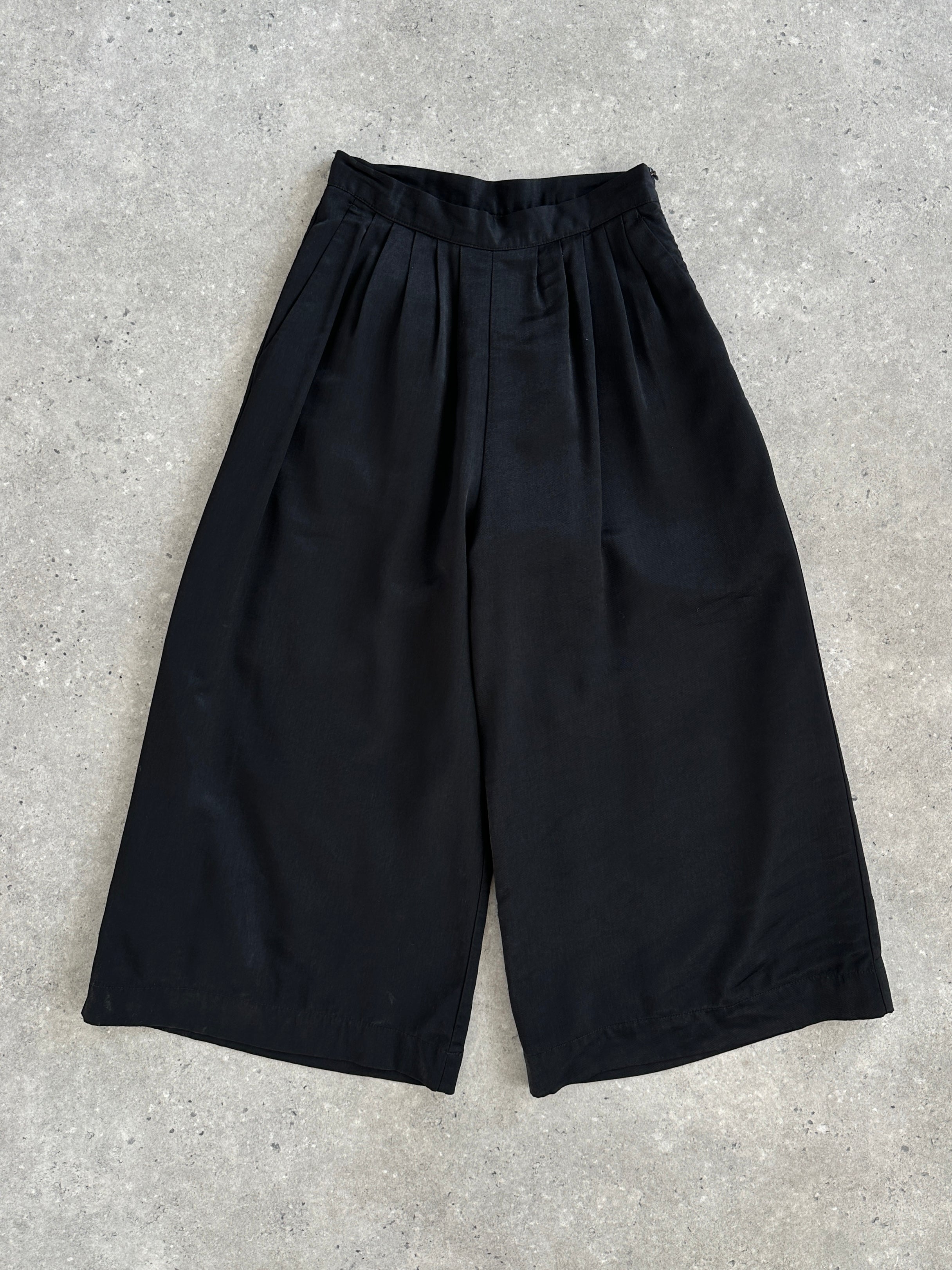 Vintage 1990s wide-leg pleated culottes shorts in W24, featuring high waist and flowy fabric, shown in natural beige fabric.