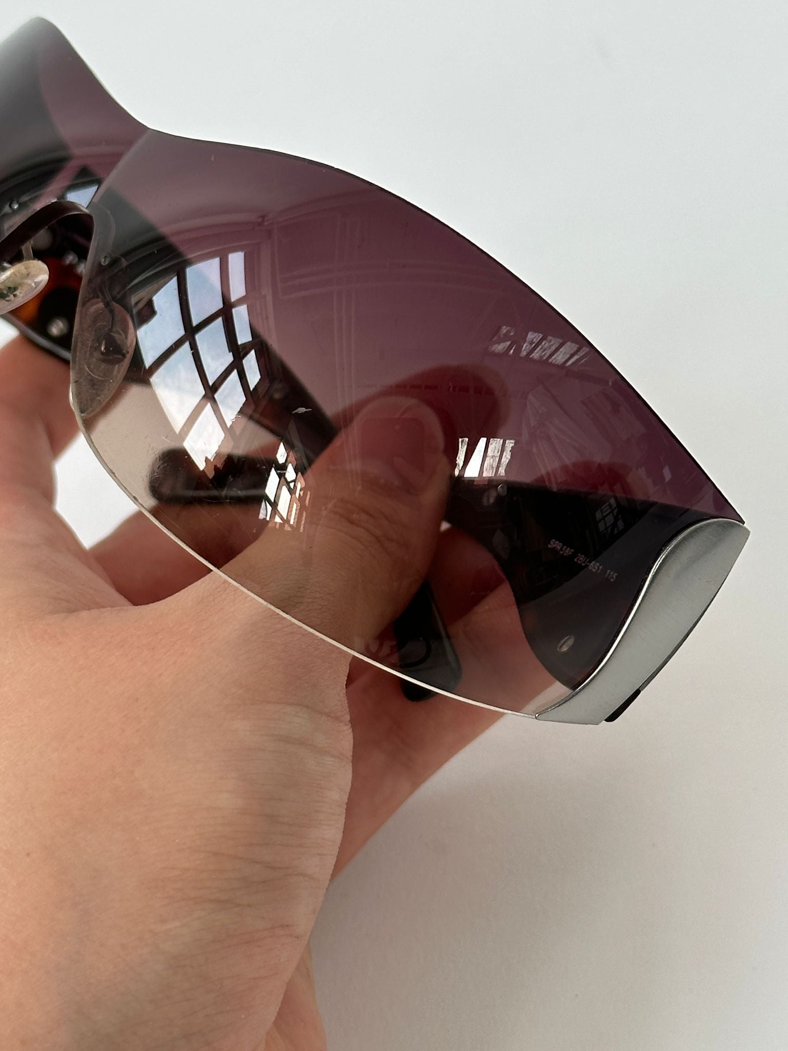 Prada Flame Rimless Wrap Sunglasses featuring sleek, modern design with tinted lenses and slim frame for stylish sun protection.