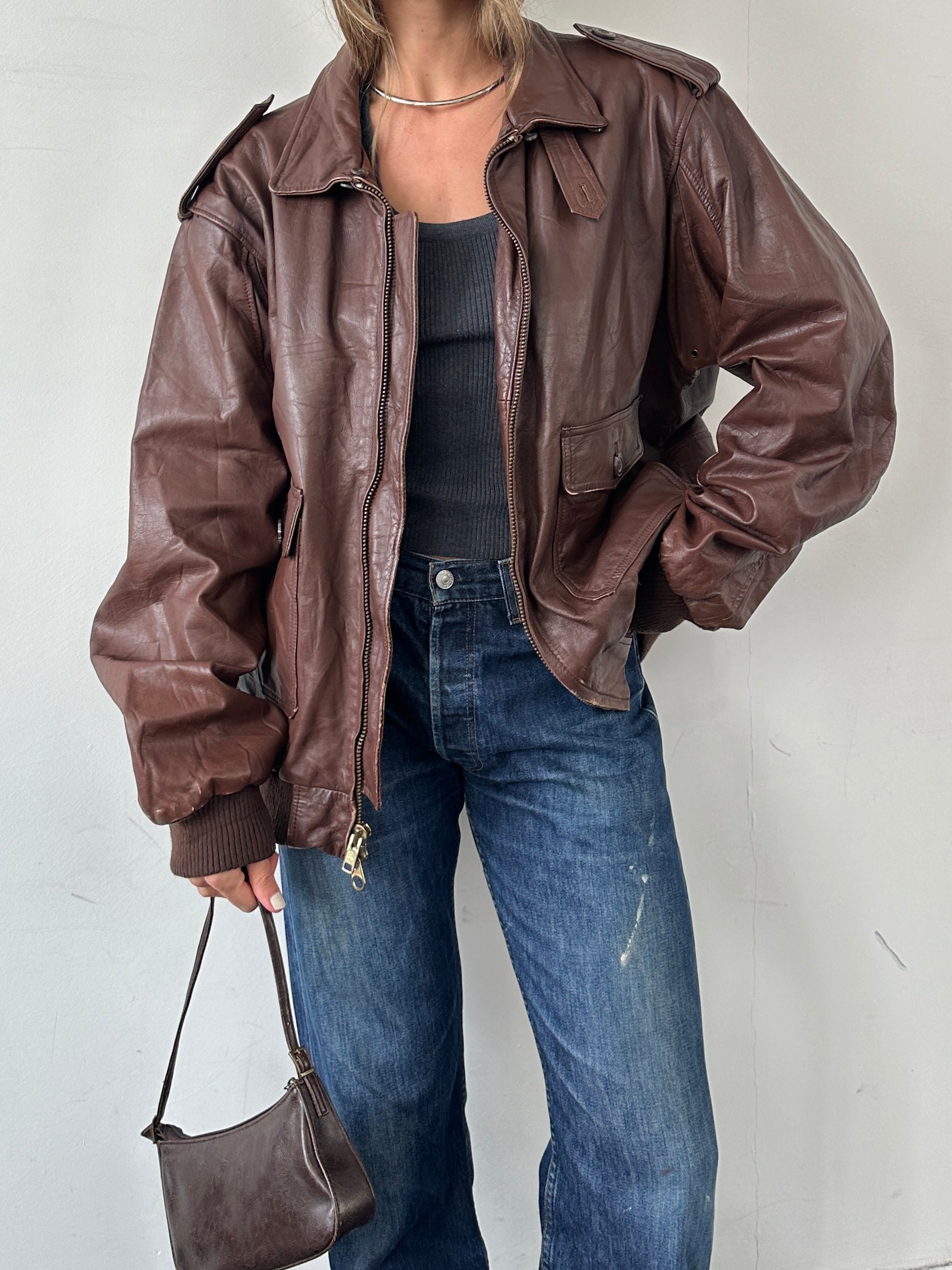 Vintage double zip leather bomber jacket in XL with classic design and smooth leather finish, displayed on a hanger.