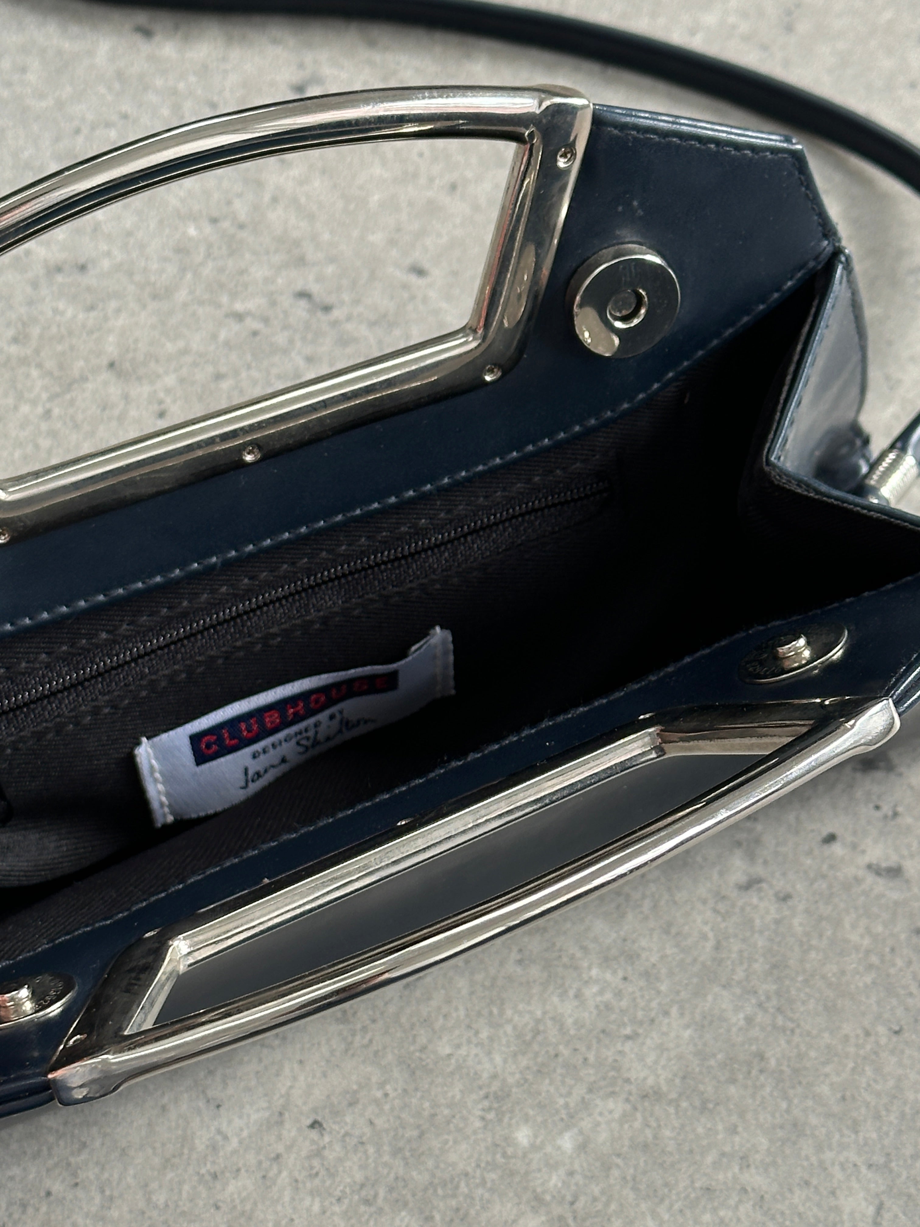 Vintage leather crossbody clutch bag with chrome accents, featuring a classic design and compact size for versatile style.