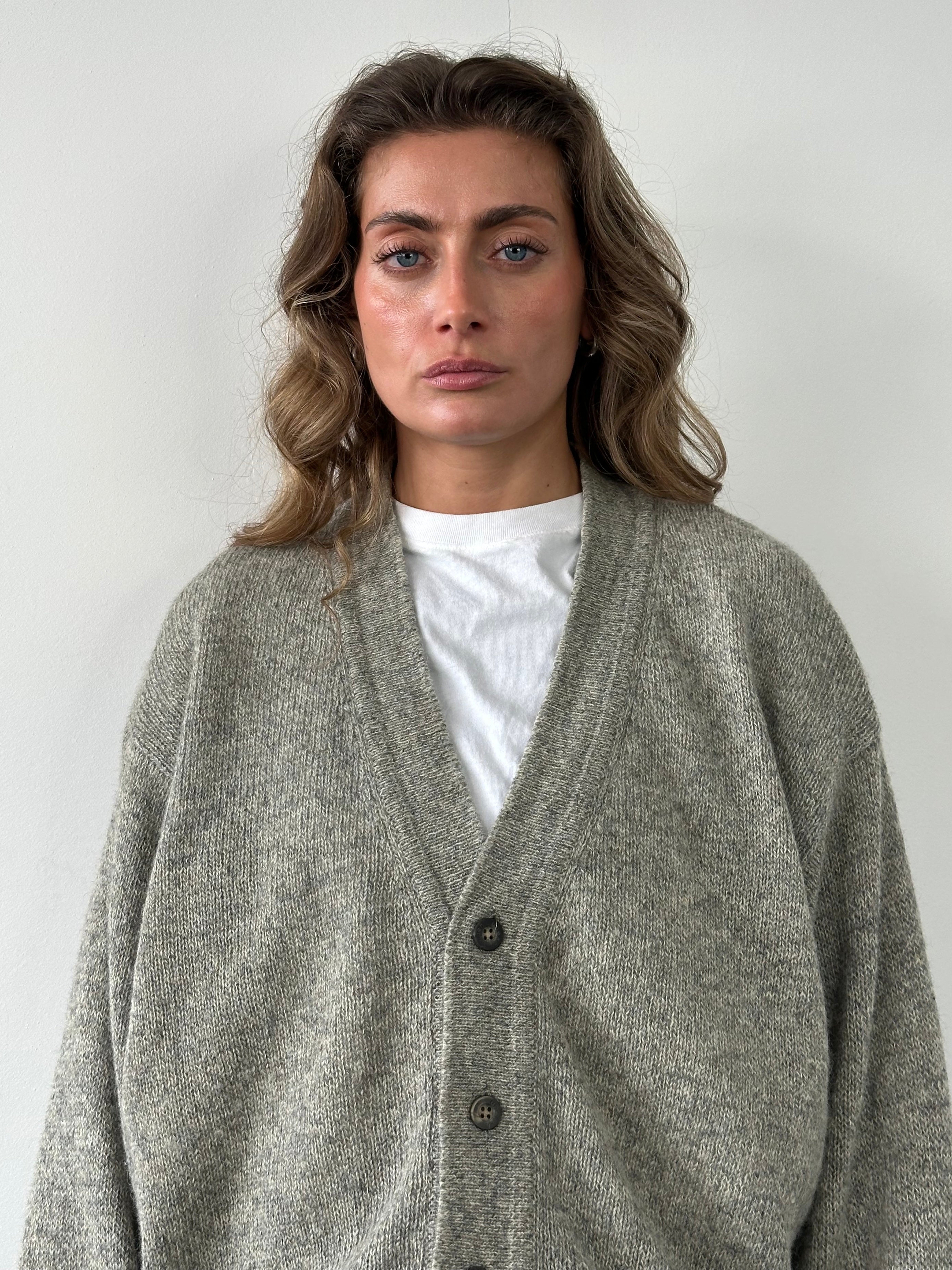 Emanuel Ungaro XL pure wool knitted cardigan displayed on a hanger, showcasing its cozy, textured knit fabric and classic design.