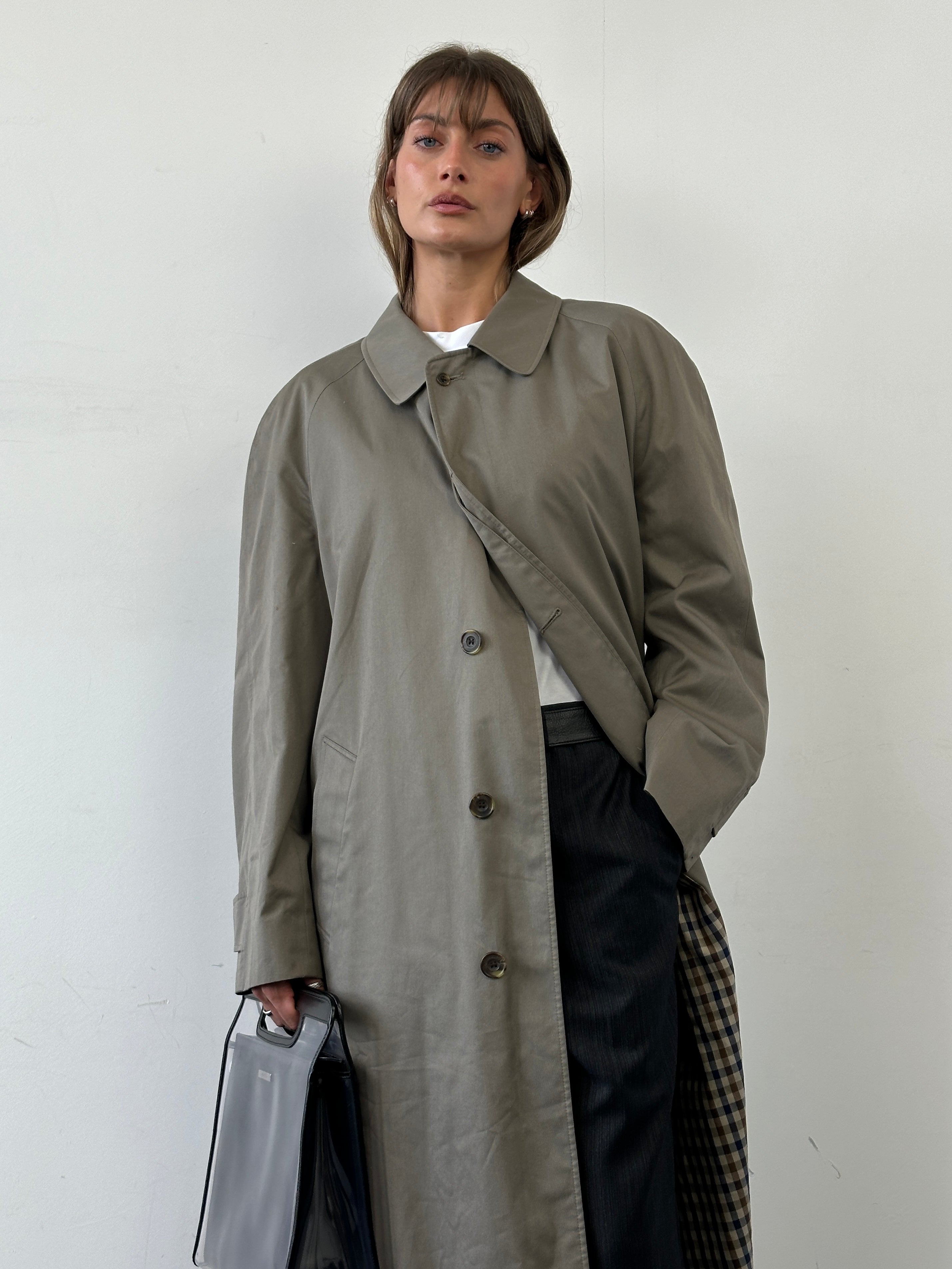 Aquascutum cotton trench coat with concealed placket in size XL, shown on a hanger with classic design and beige color.