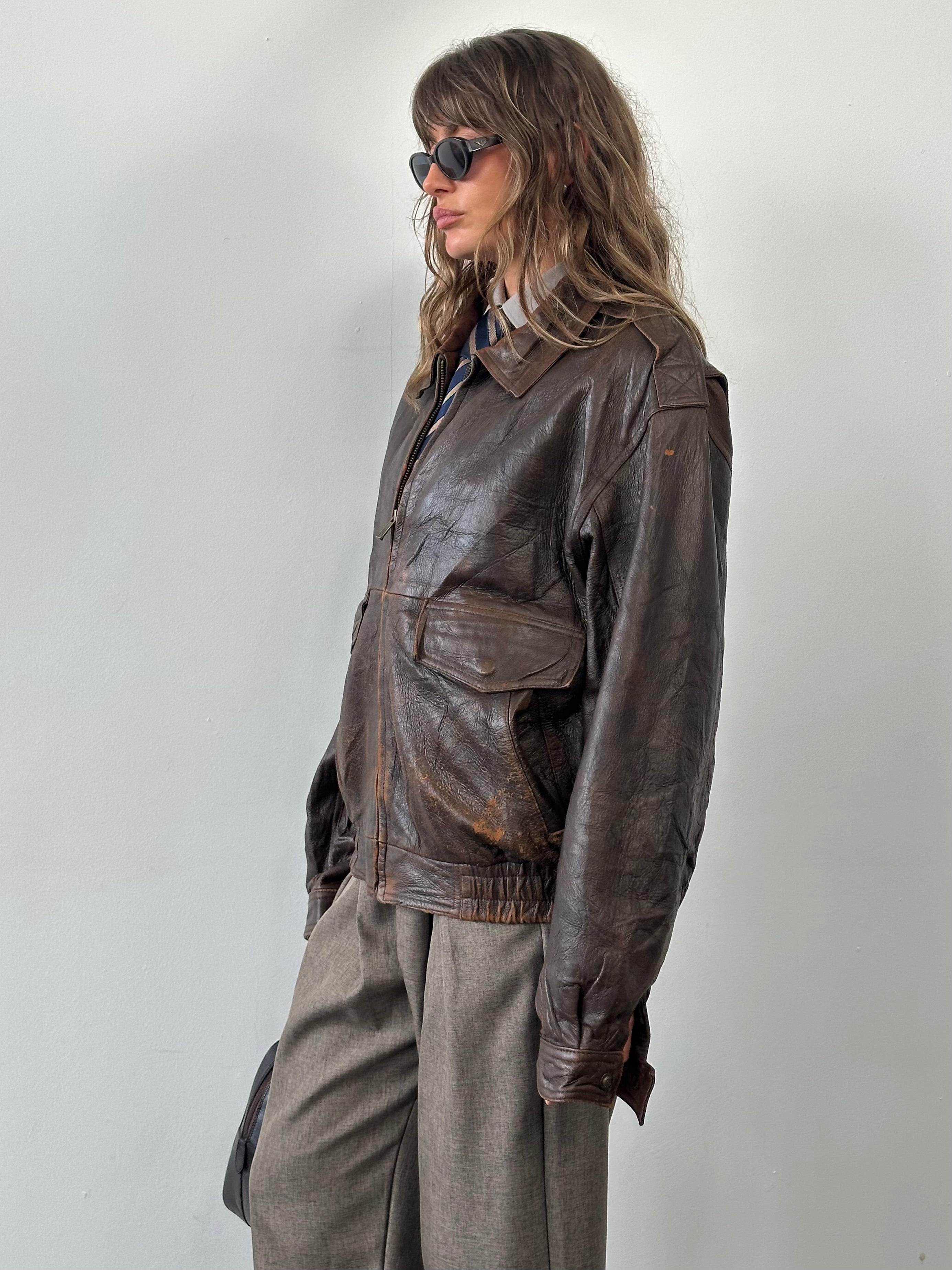 Vintage 1990s distressed leather bomber jacket in size XL, featuring a rugged, worn-in look and classic style.