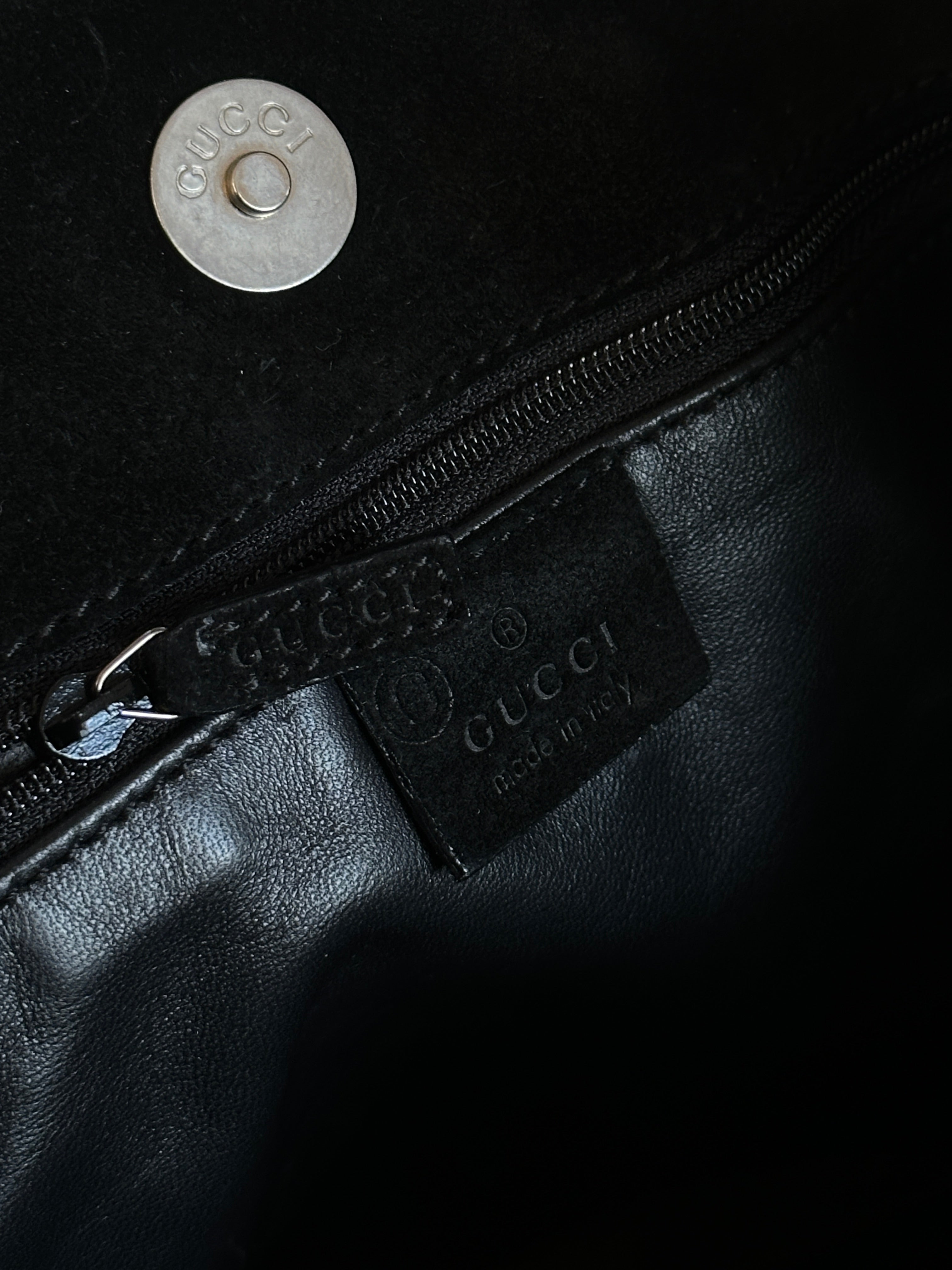 Gucci suede shoulder bag with gold-tone hardware and adjustable strap, featuring a sleek and stylish design.