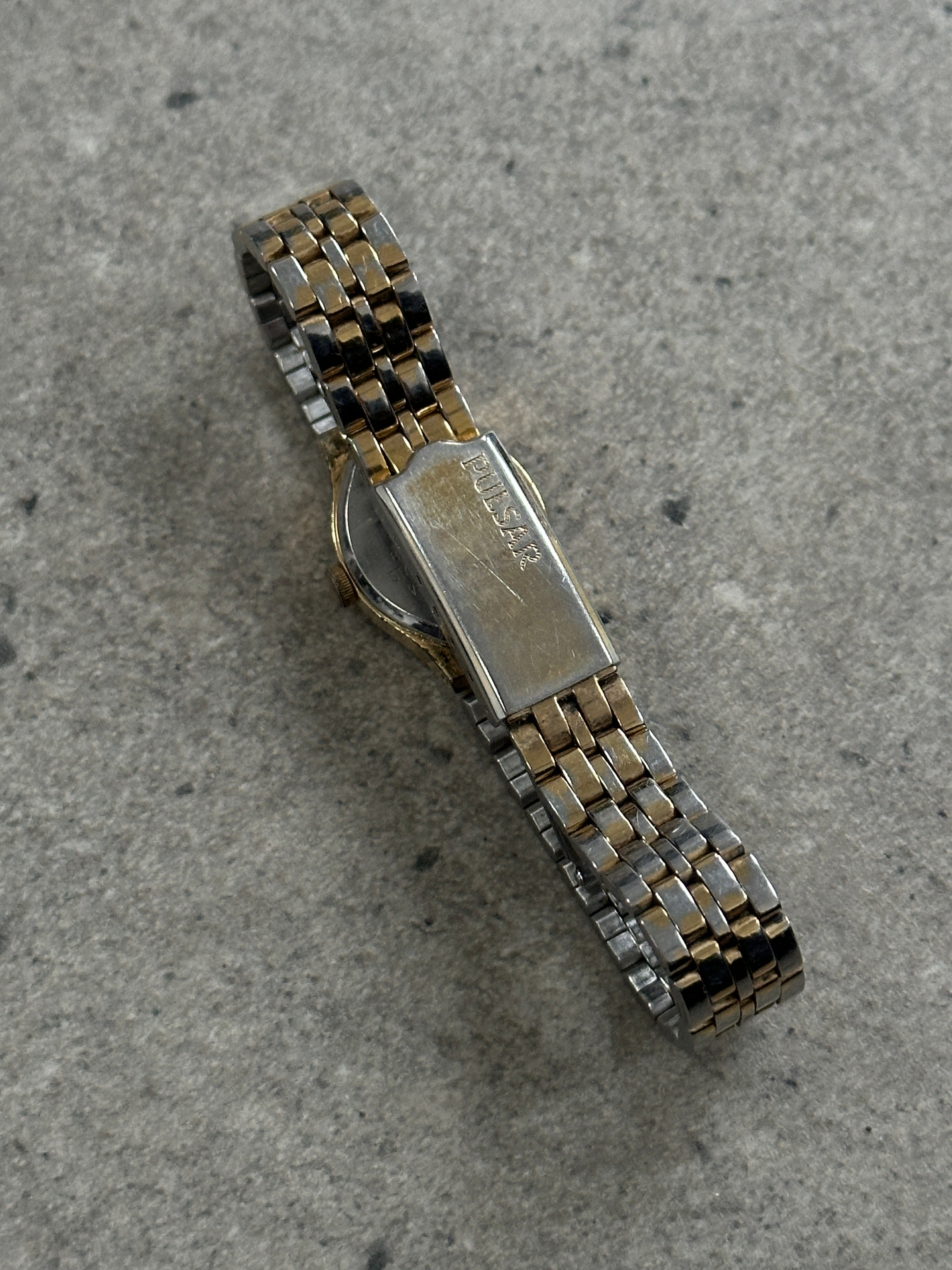 Pulsar 1990s two-tone round quartz watch with silver and gold accents, featuring a sleek analog dial and stainless steel band