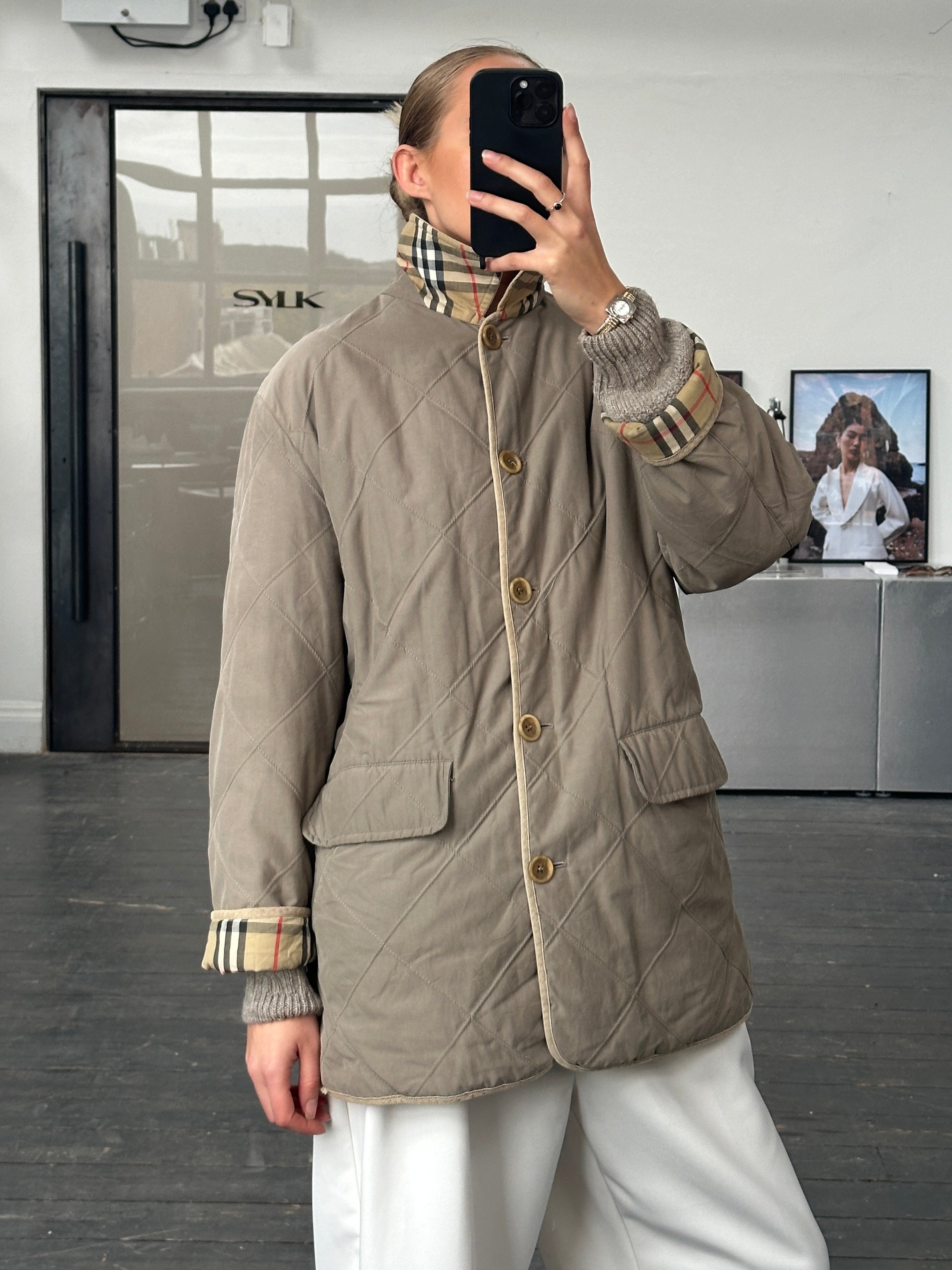 Burberry 1990s quilted Nova Check cord collar coat displayed on a hanger, showcasing classic pattern and stylish design.
