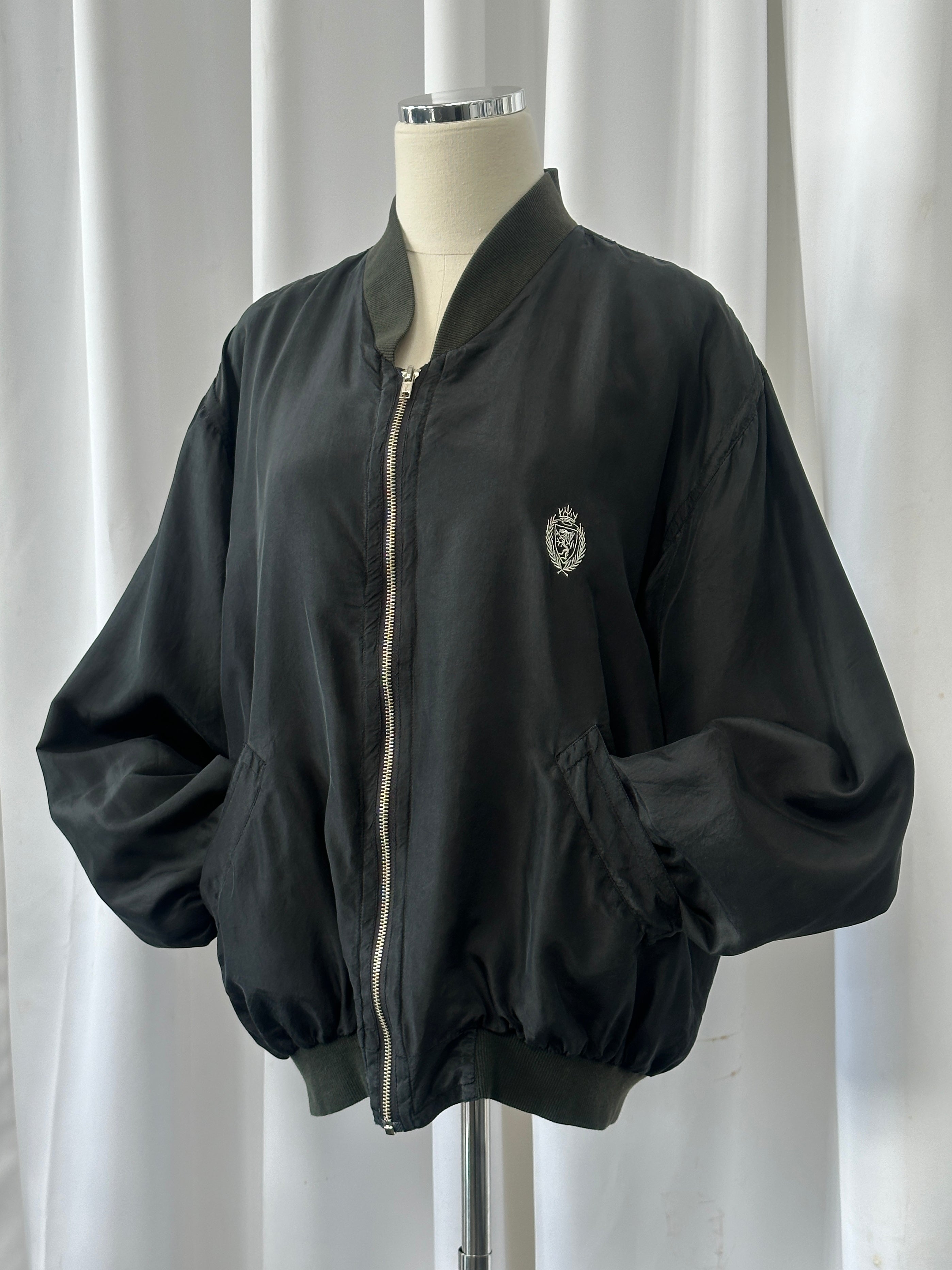 Vintage 1990s pure silk bomber jacket, M/L size, with classic style and smooth fabric, displayed on a hanger.
