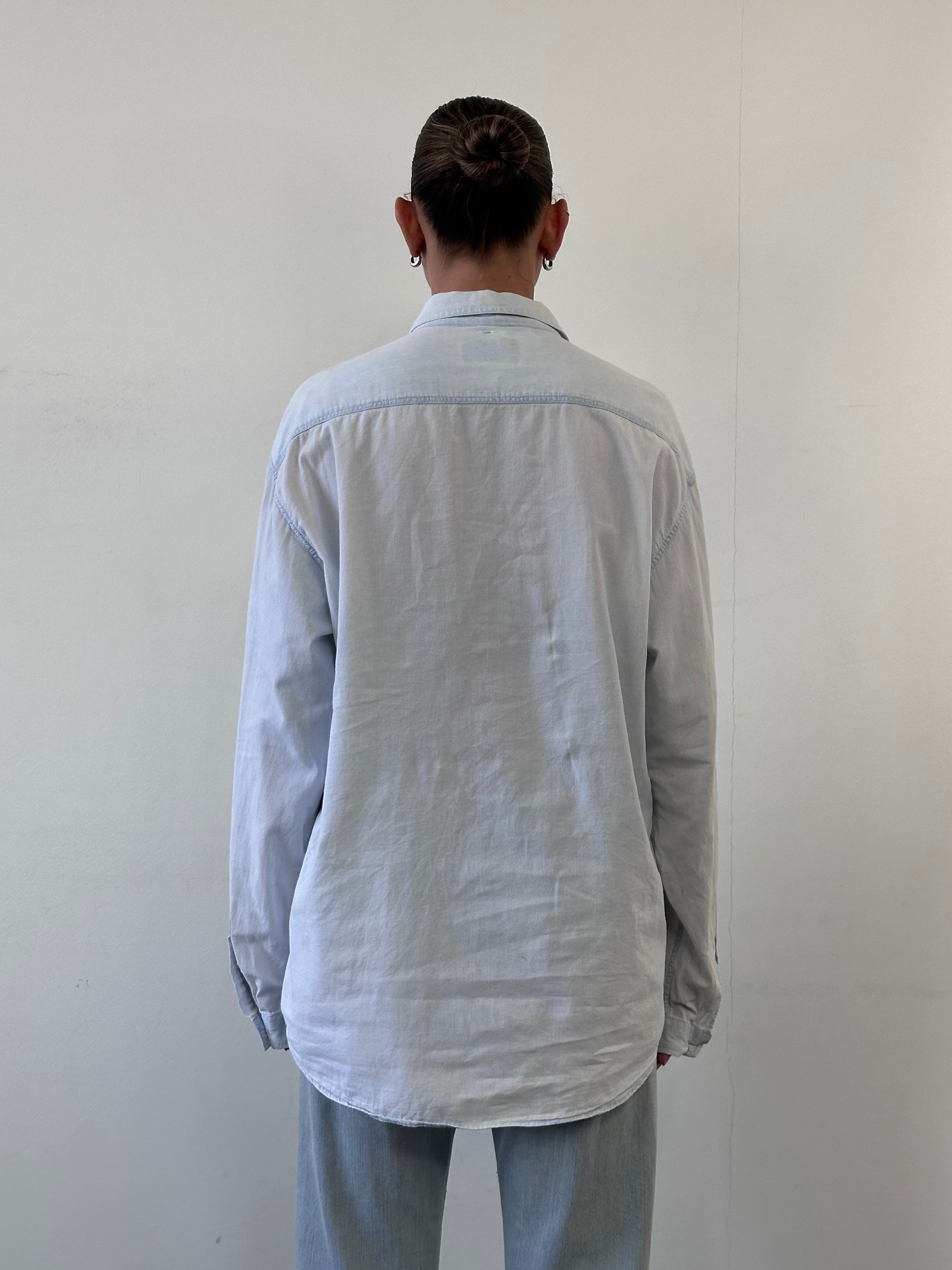 Armani Jeans light wash denim shirt in XL size, featuring classic button-down style and chest pockets, displayed on a hanger.