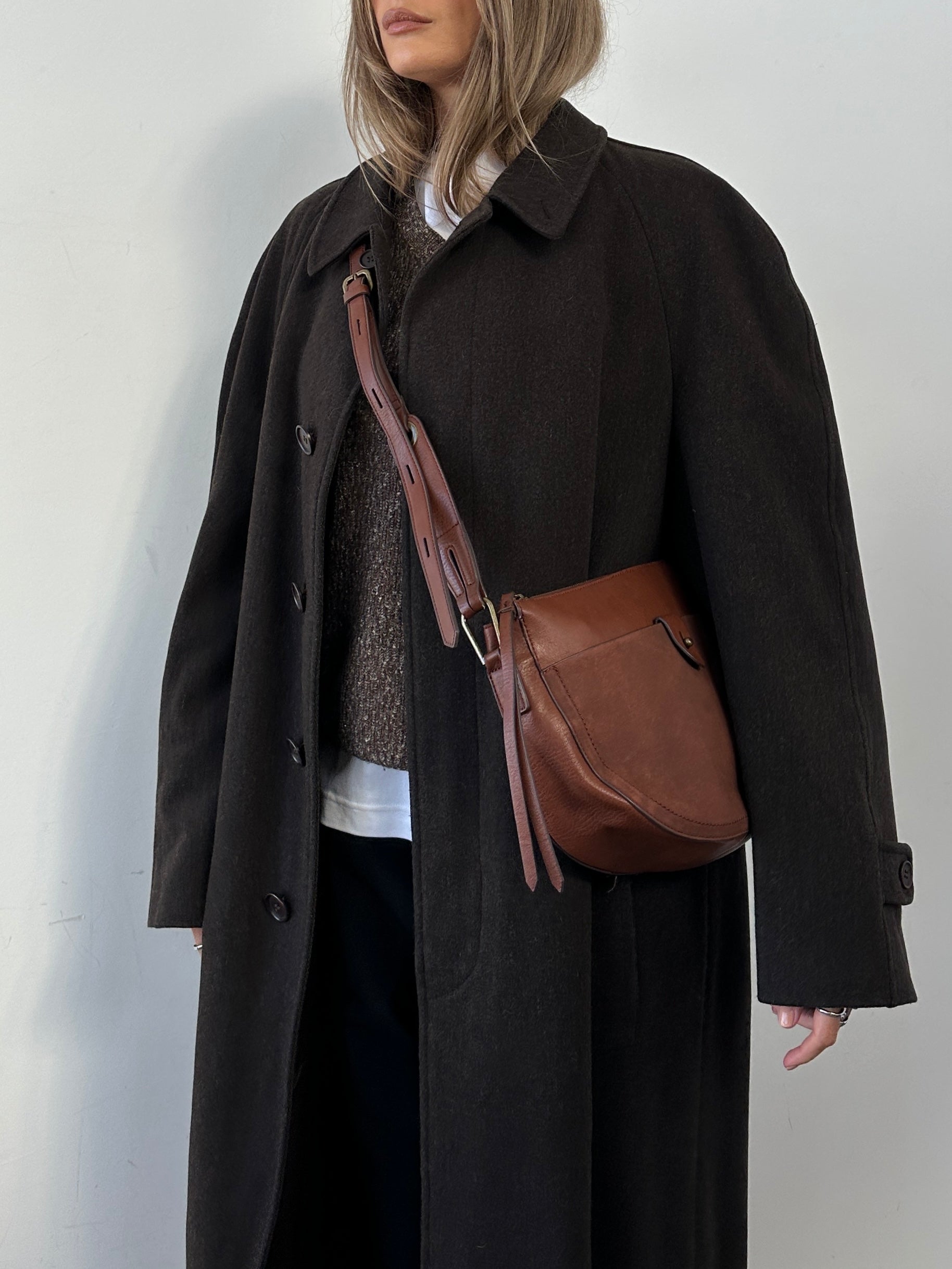 Vintage faux leather crescent crossbody bag showing its curved shape and textured surface with a sleek strap.