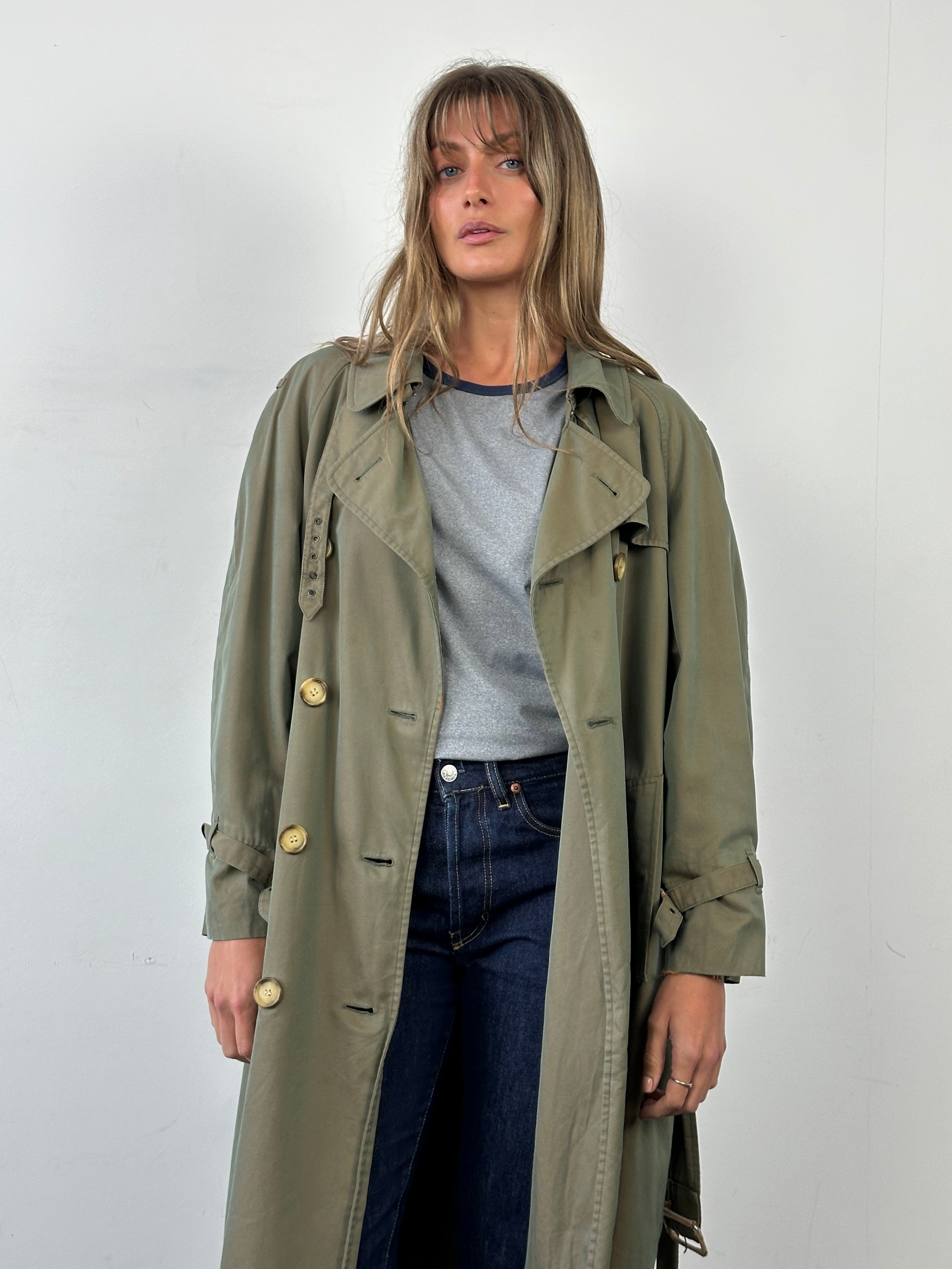 Yves Saint Laurent Rive Gauche 1980s double-breasted trench coat in beige, stylish and elegant, shown hanging on a clothing rack.