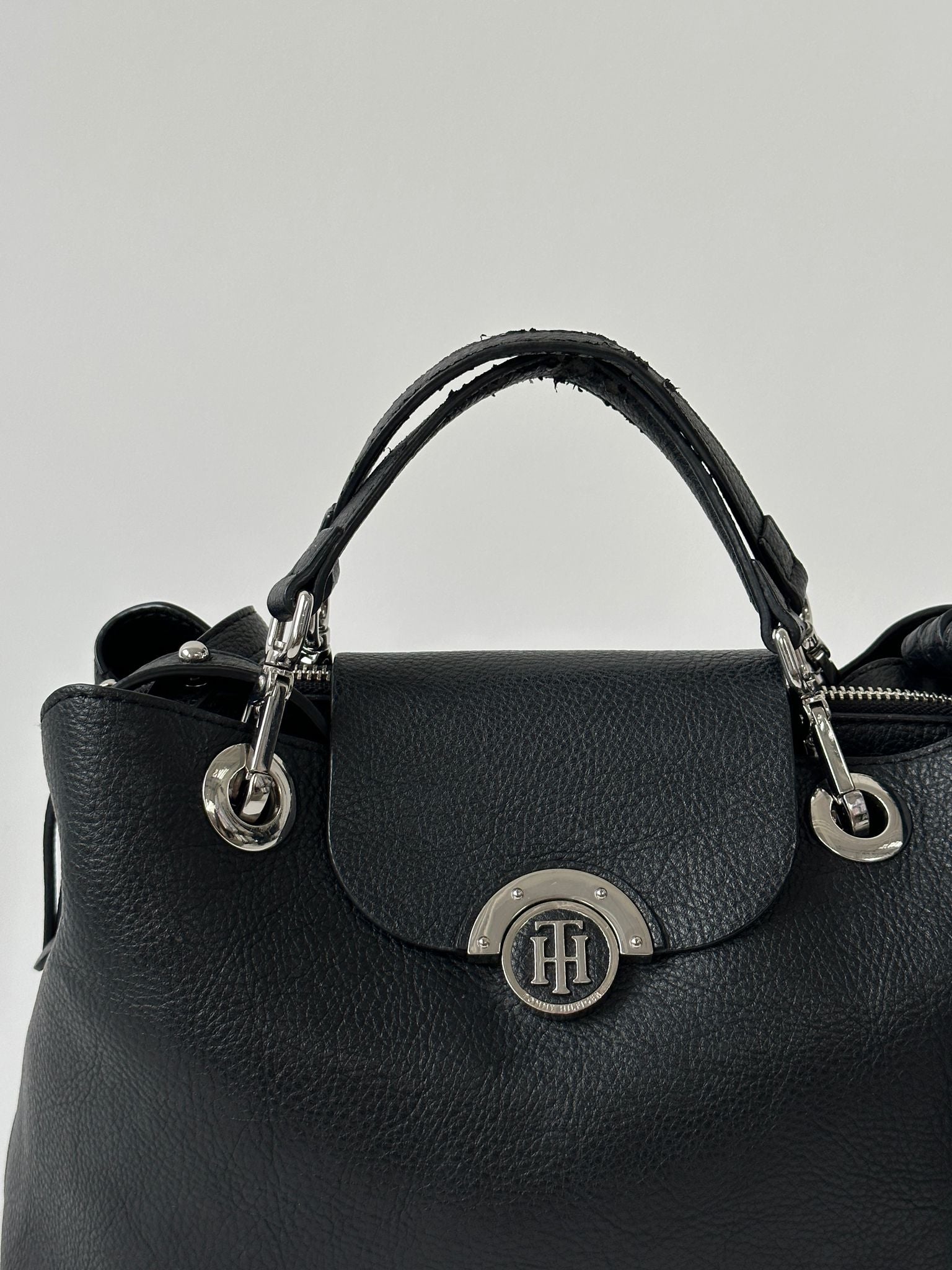 Tommy Hilfiger crossbody bag with adjustable strap, featuring classic logo design and stylish fabric in a close-up image.