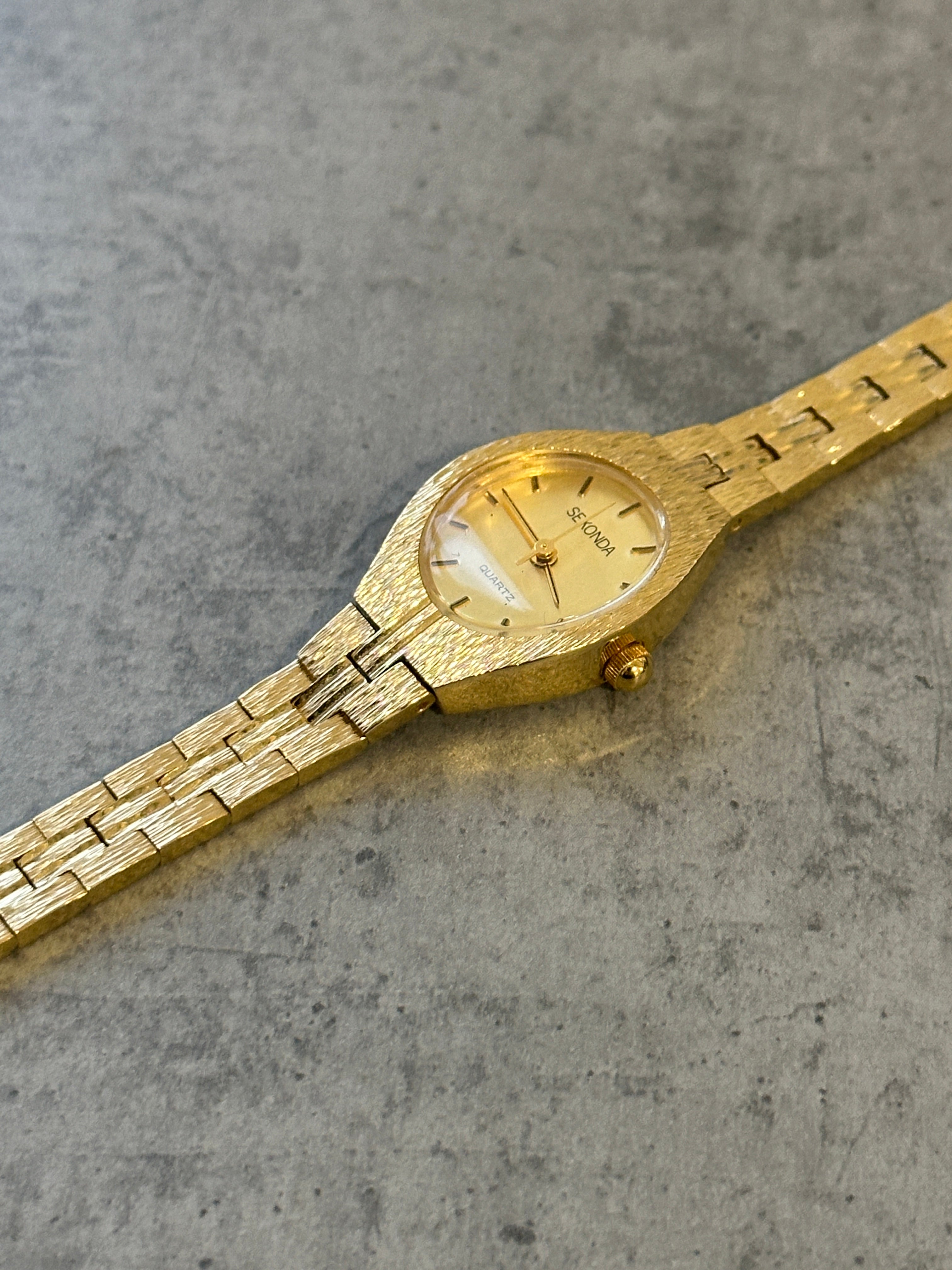 Sekonda 1990s gold-tone quartz watch with a round dial and metal bracelet, showcasing vintage style and classic design.