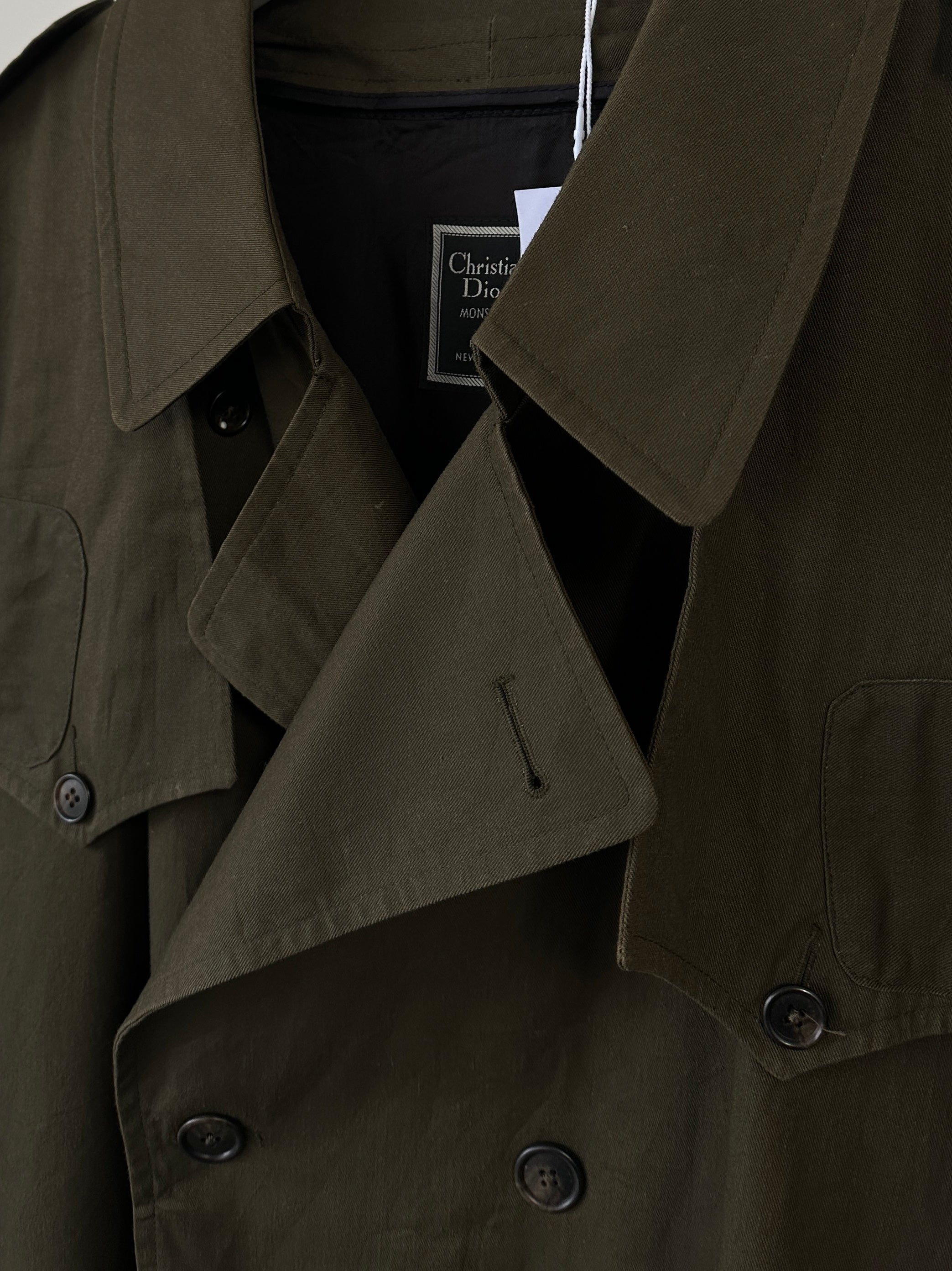 Christian Dior cotton double-breasted trench coat in size XL hanging on a hanger, showcasing classic design and tailored fit.
