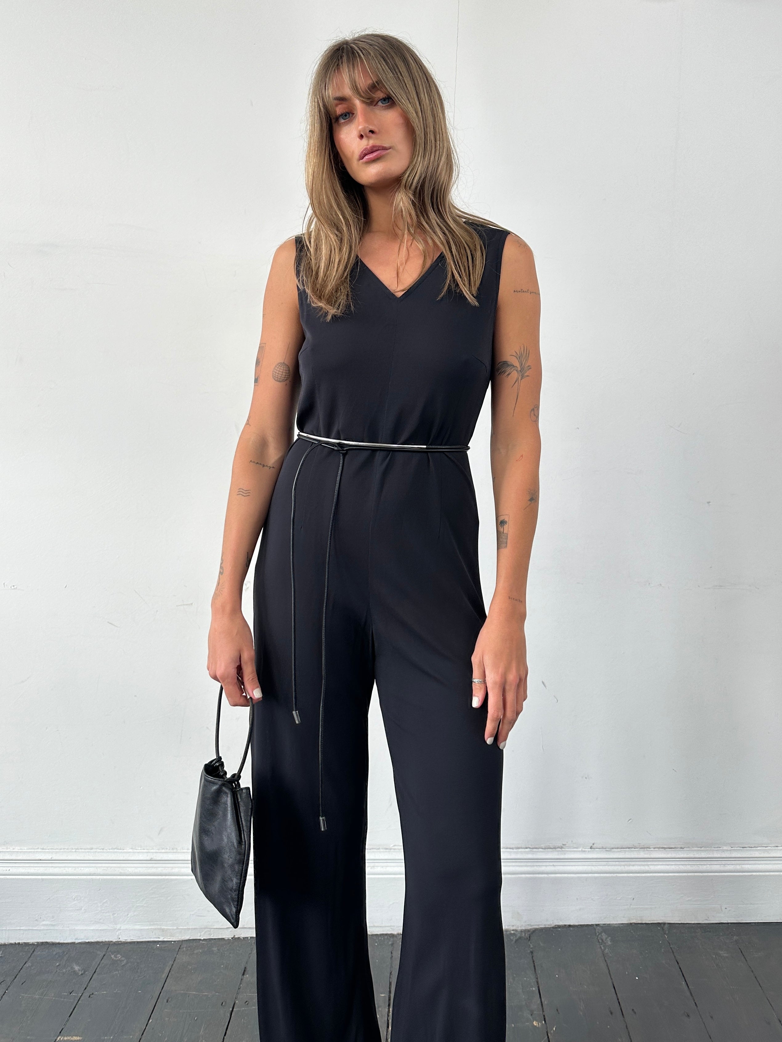 Vintage 80s V-neck stretch jumpsuit in black, fitted with wide legs and short sleeves, displayed on a mannequin.