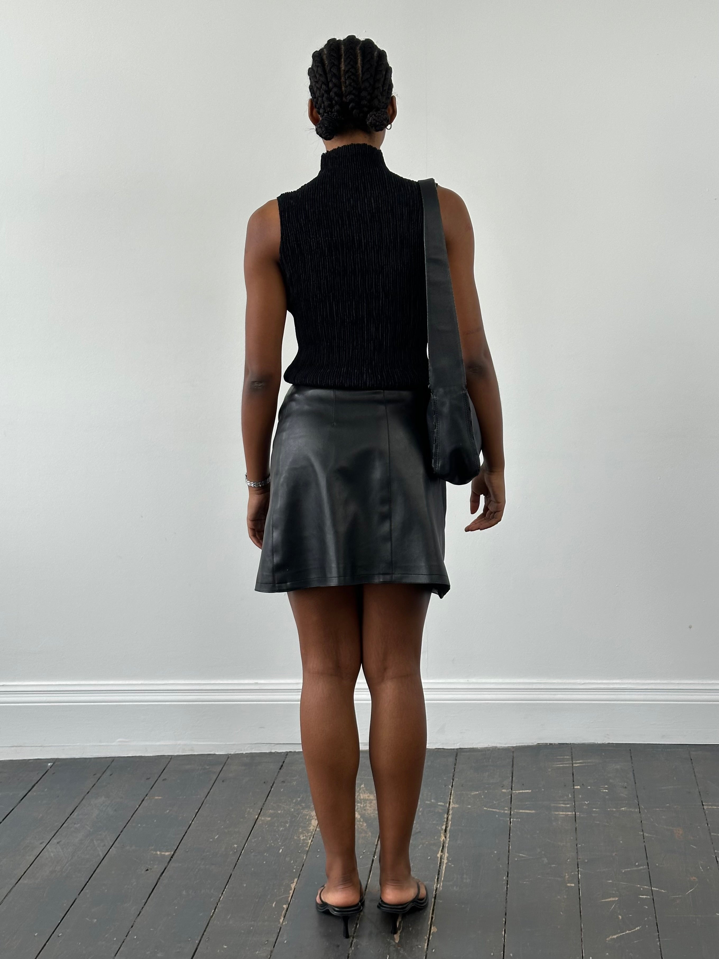 Vintage faux leather wrap mini skirt, W25, showcasing its textured black material and stylish design.