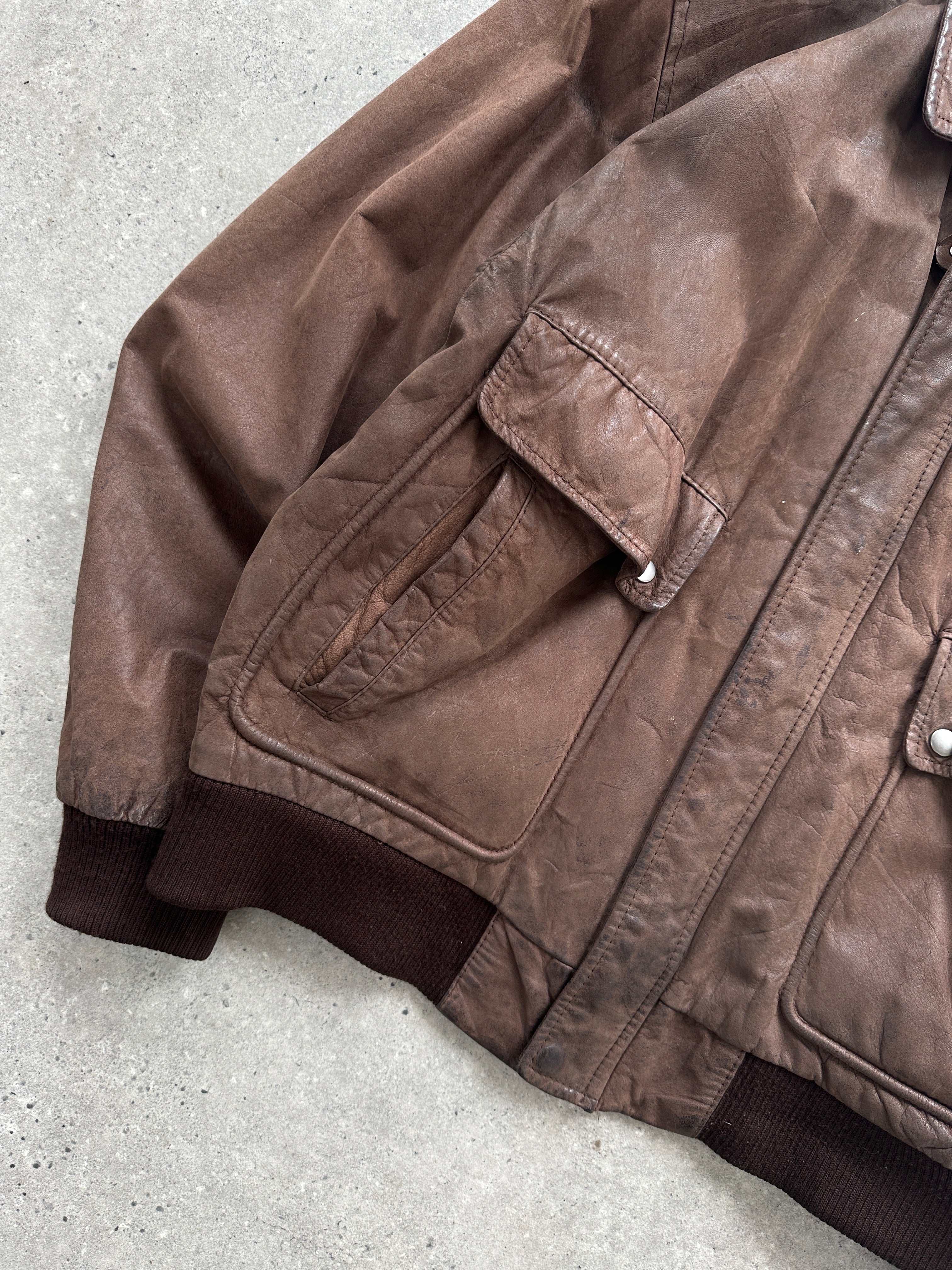 Vintage distressed leather bomber jacket, size L, featuring a rugged design with ribbed cuffs and collar, vintage style and authentic leather.