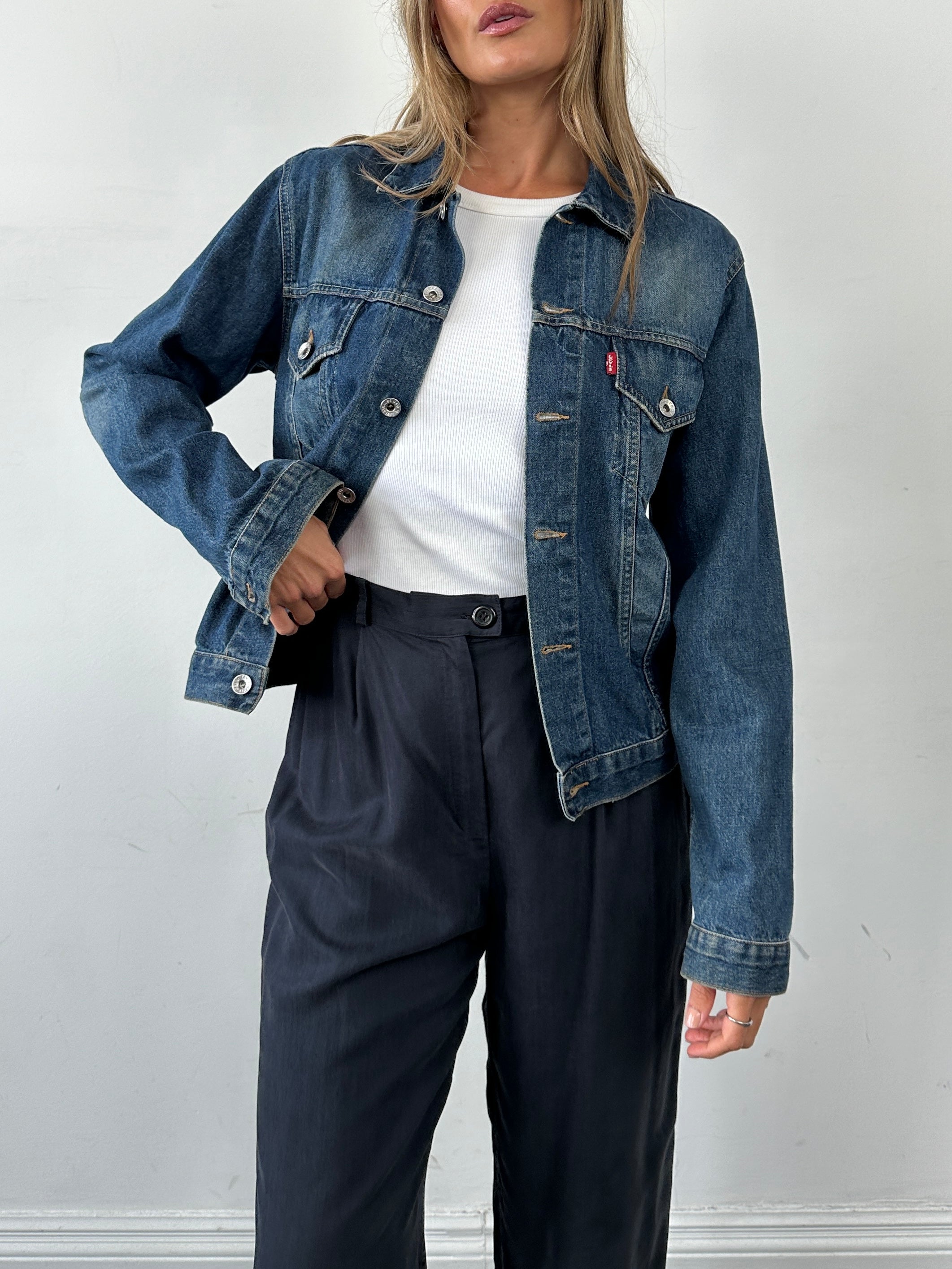 Levi’s faded denim jacket in size small, featuring classic design and distressed look, displayed on a hanger.