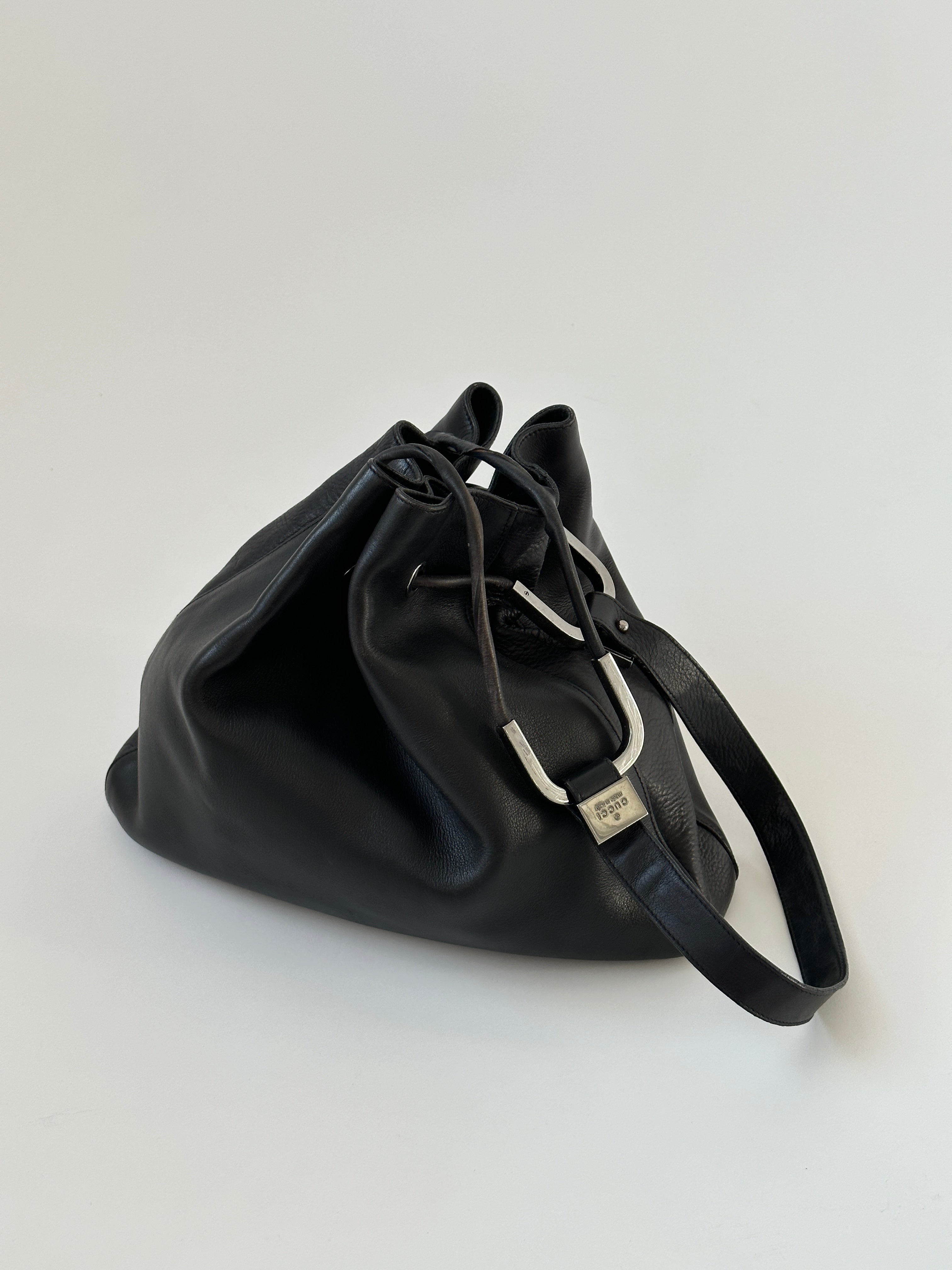 Gucci leather bucket bag with adjustable strap and gold-tone hardware, featuring a sleek, stylish design.