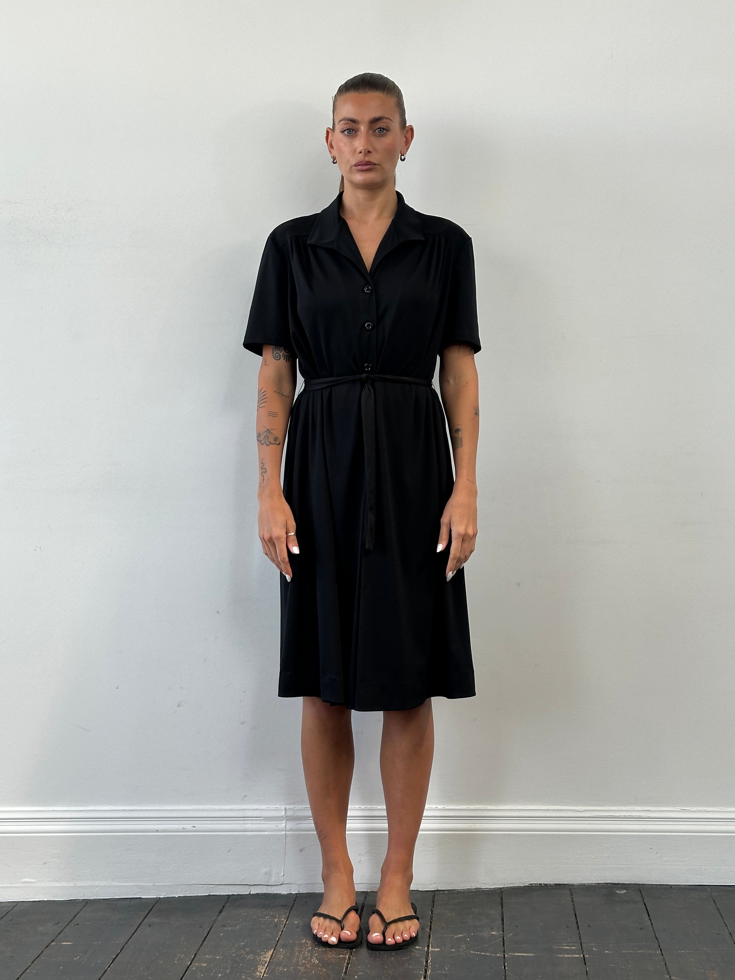 Vintage 1990s belted short sleeve midi shirt dress hanging on a hanger, showcasing its classic design and vintage fabric.
